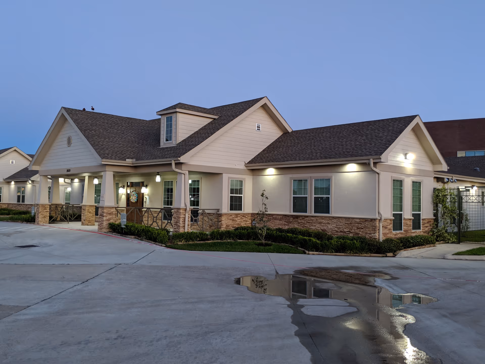 Exterior of a single-story senior living facility with a covered porch and neutral siding.