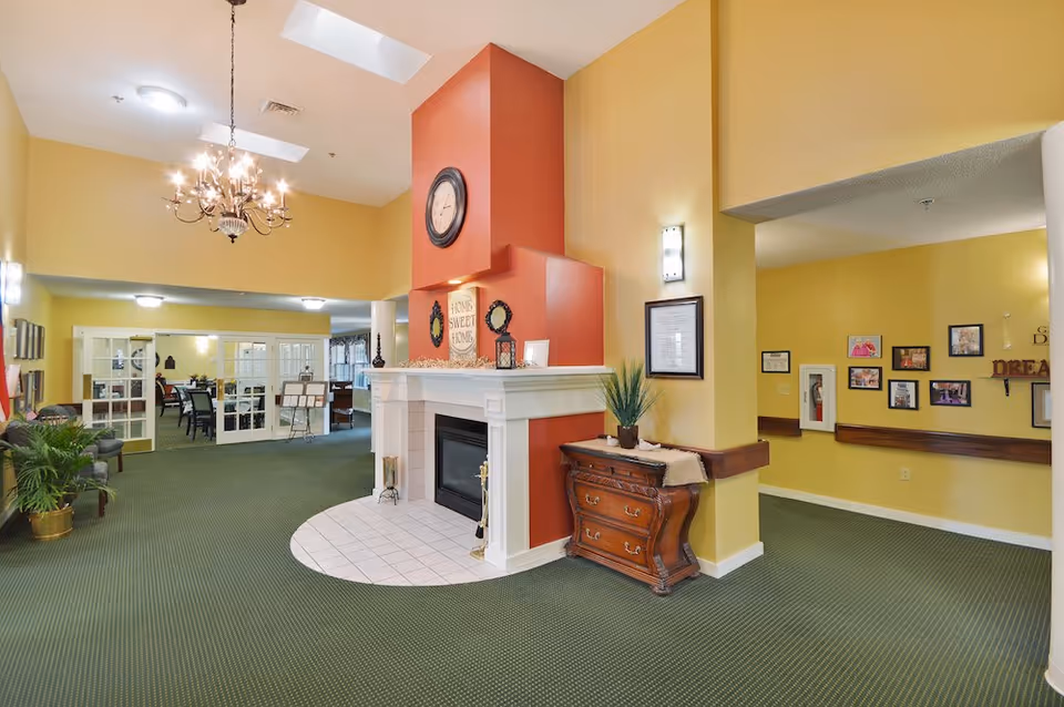 American House Kingsport lobby: yellow walls, fireplace, chandelier, green carpet, and seating.