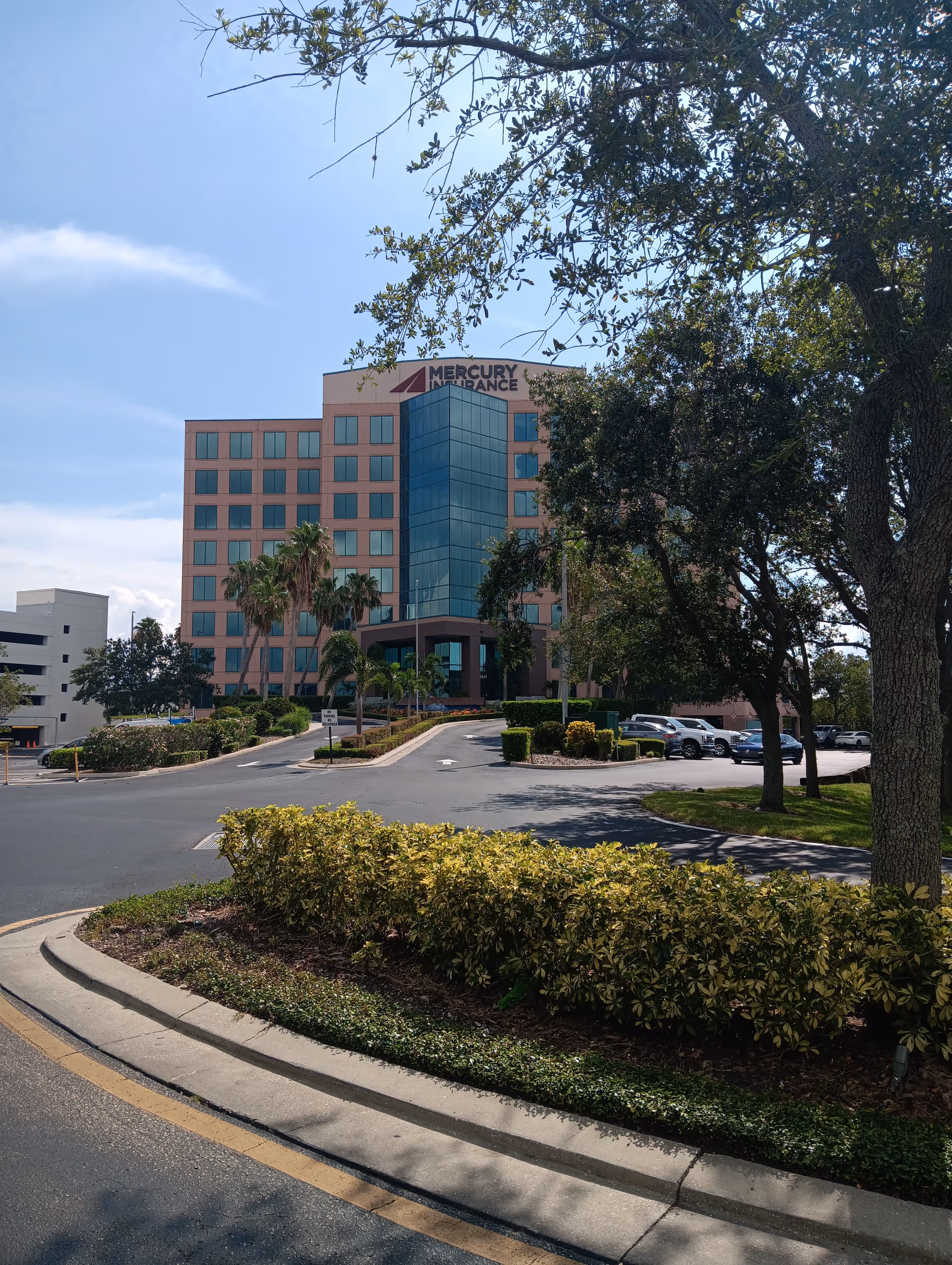 Front view of a beige office building with a blue glass central section.
