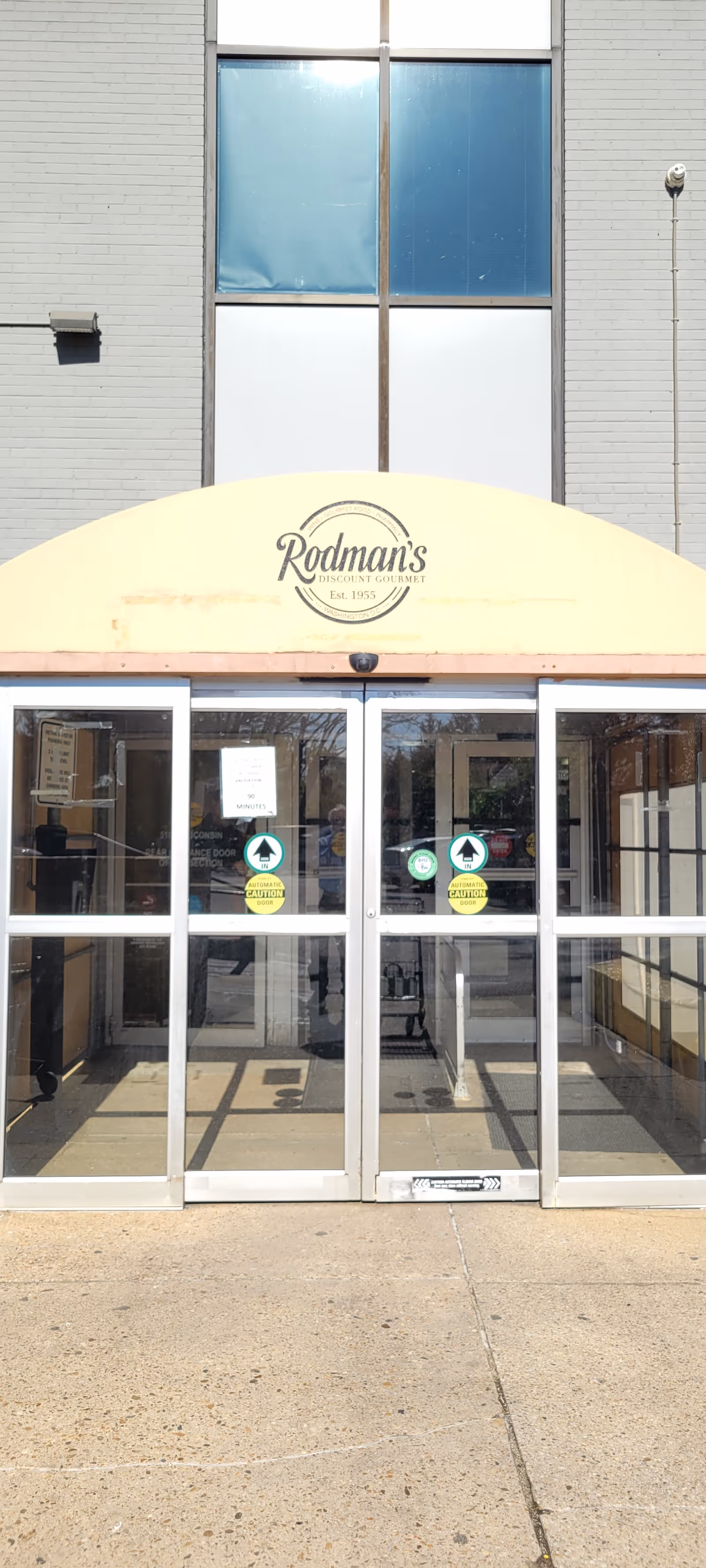 Glass doors of Rodman's facility beneath a yellow awning with the Rodman's sign.