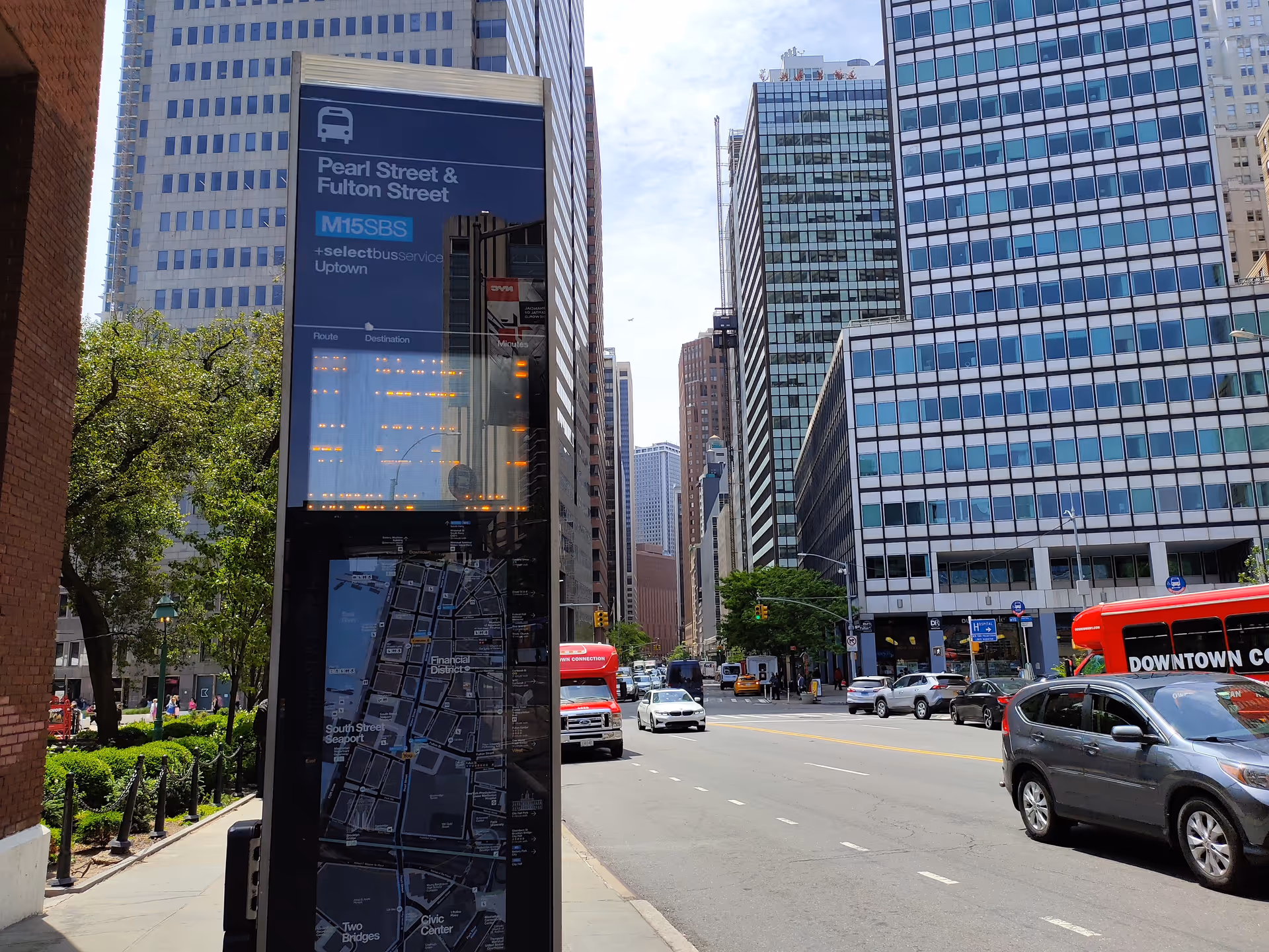 Urban street scene with tall glass buildings and a roadside map sign.