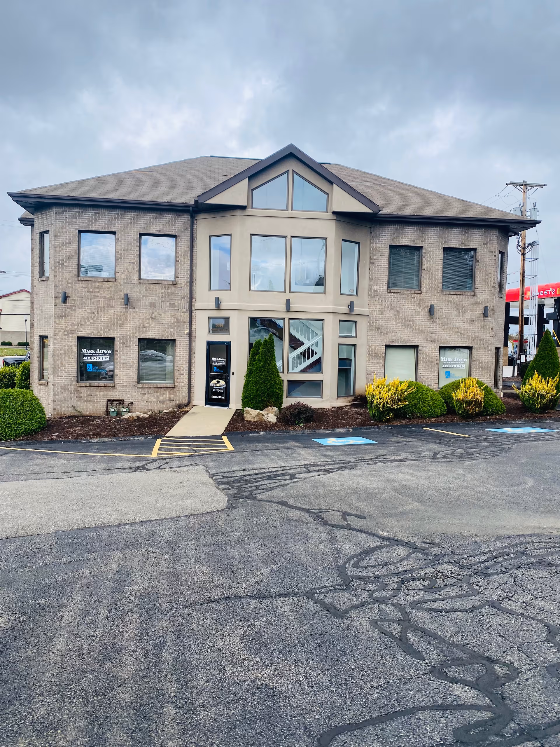 Exterior view of a two-story brick senior living facility with a central glass entrance.