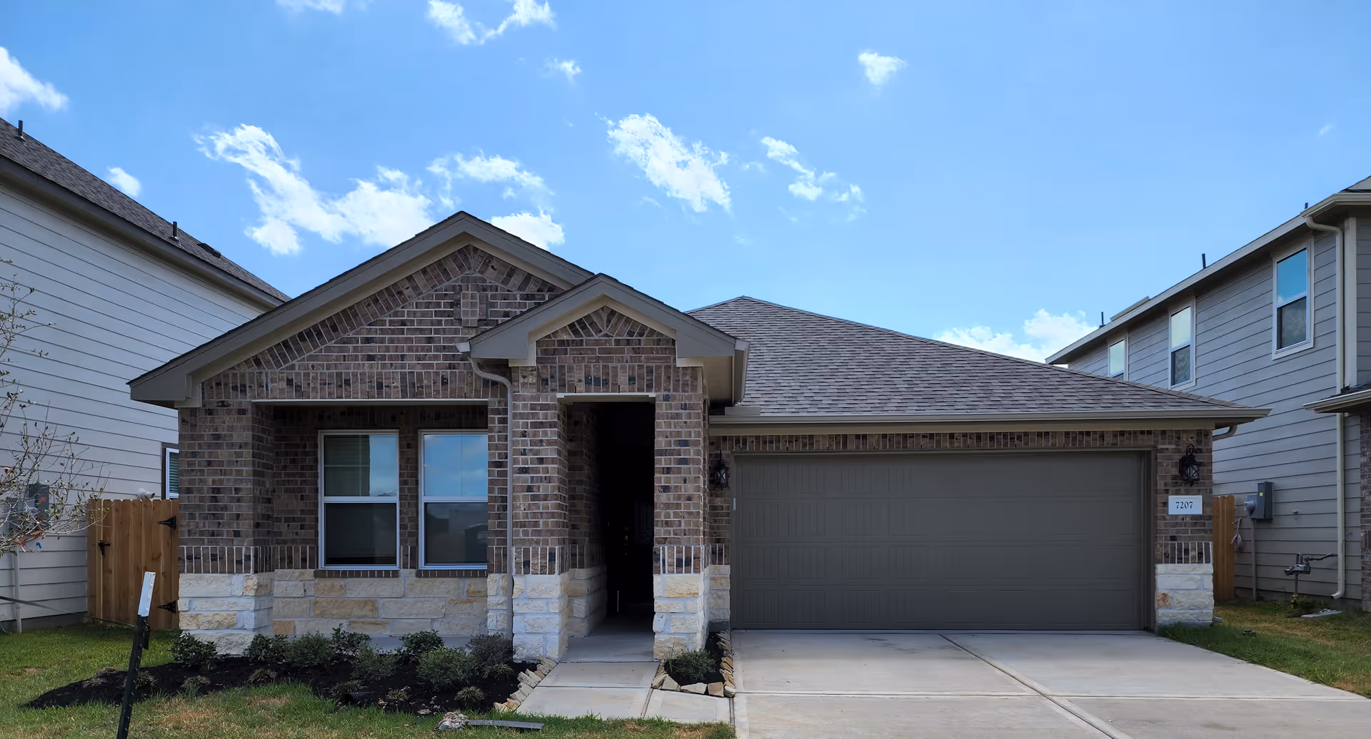 Front view of a brick, single-story house with a two-car garage and entryway.