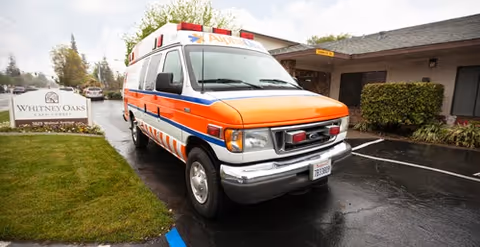 An ambulance parked in front of the Whitney Oaks Care Center entrance.