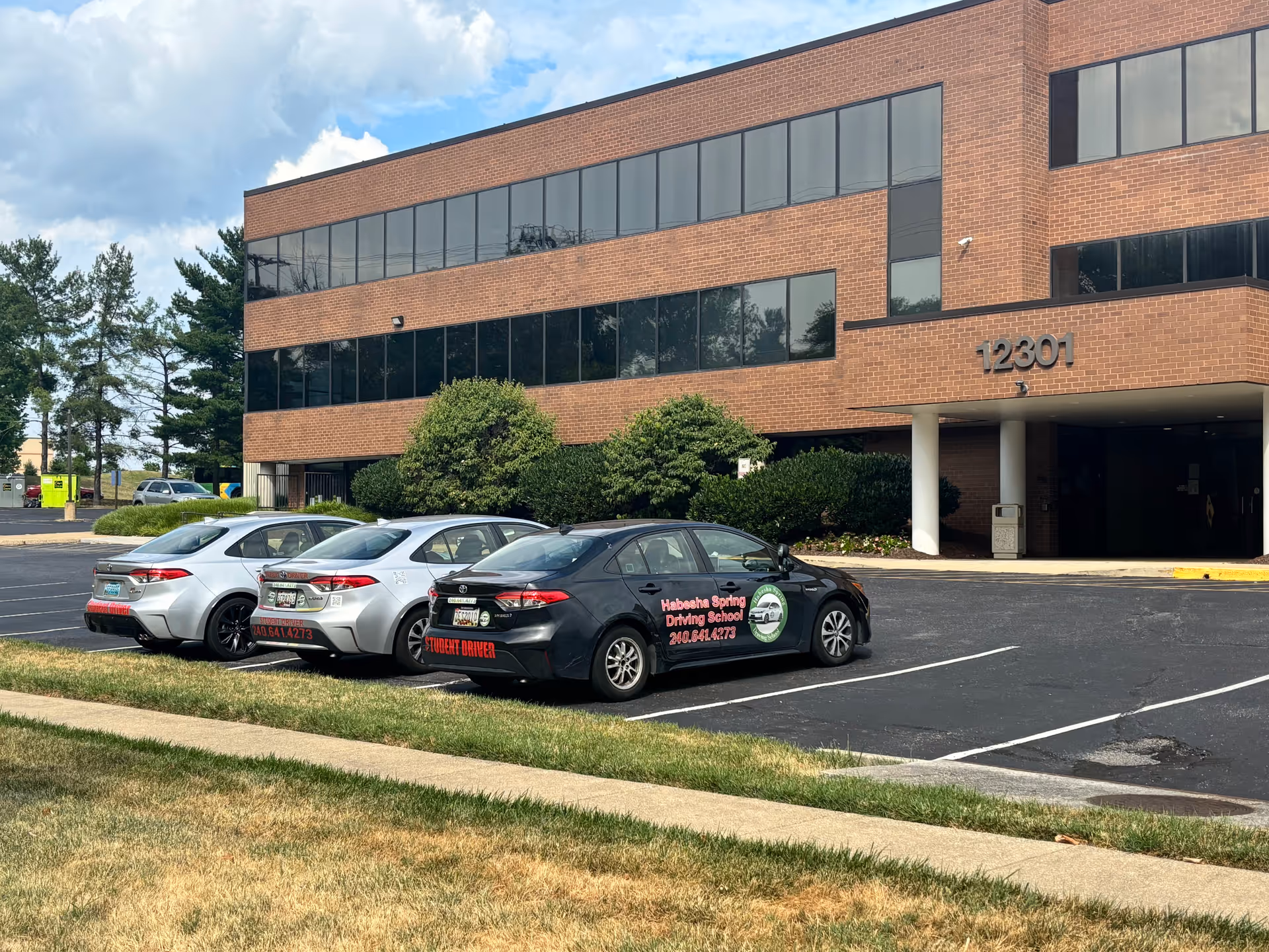 Exterior view of a brick office building with a parking lot and several cars.