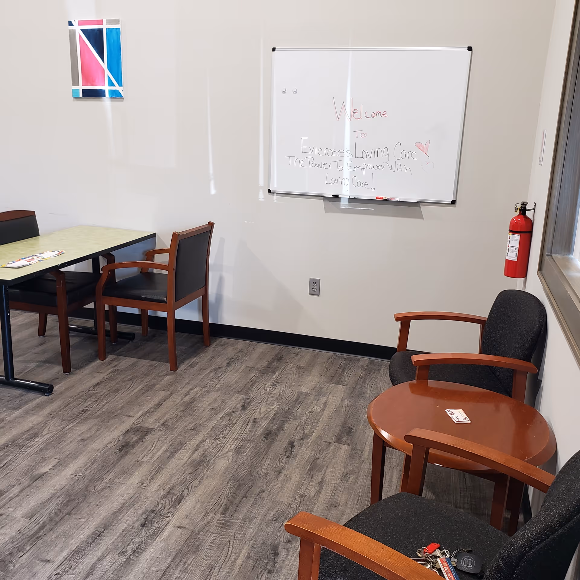 Interior common area with a whiteboard, seating, and a fire extinguisher in a senior living facility.