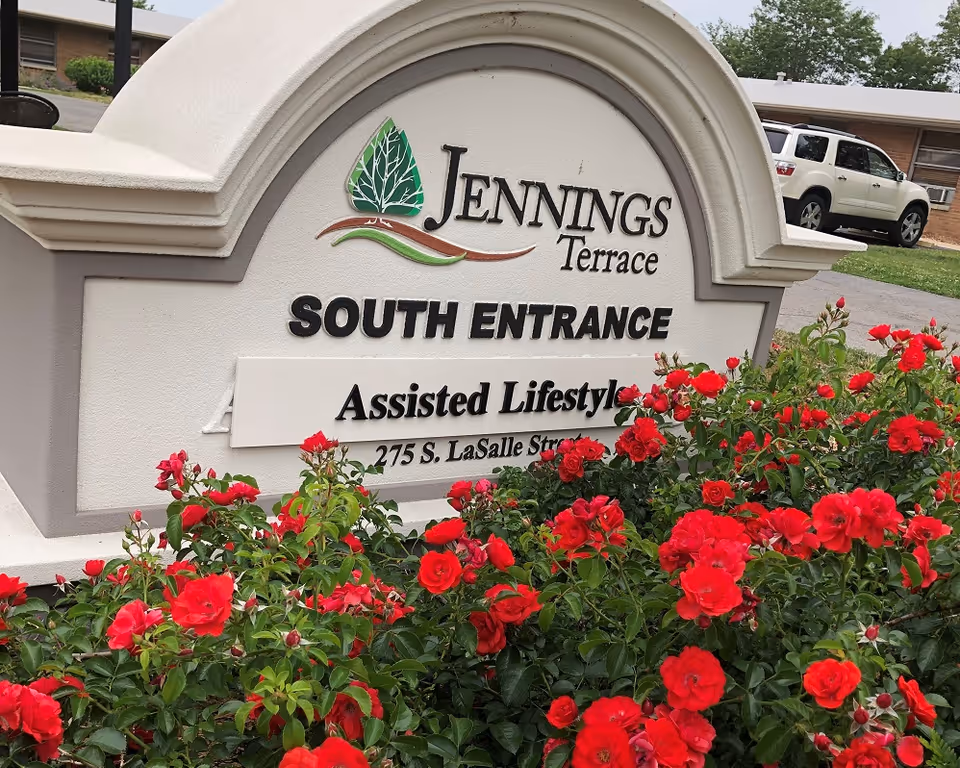 Exterior sign for Jennings Terrace South Entrance with red roses.