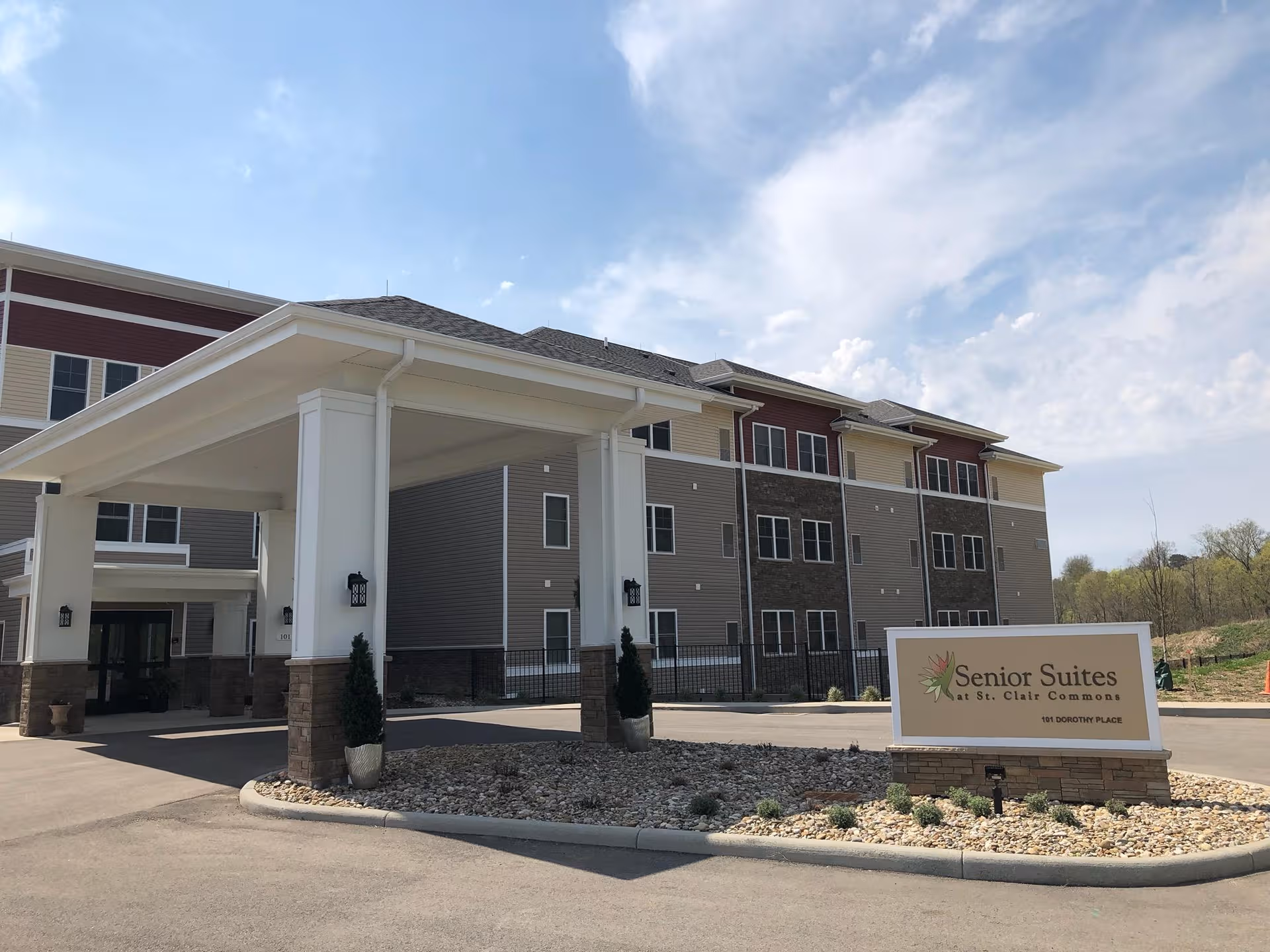 Wide view of Senior Suites at St. Clair Commons exterior with a porte-cochere and sign