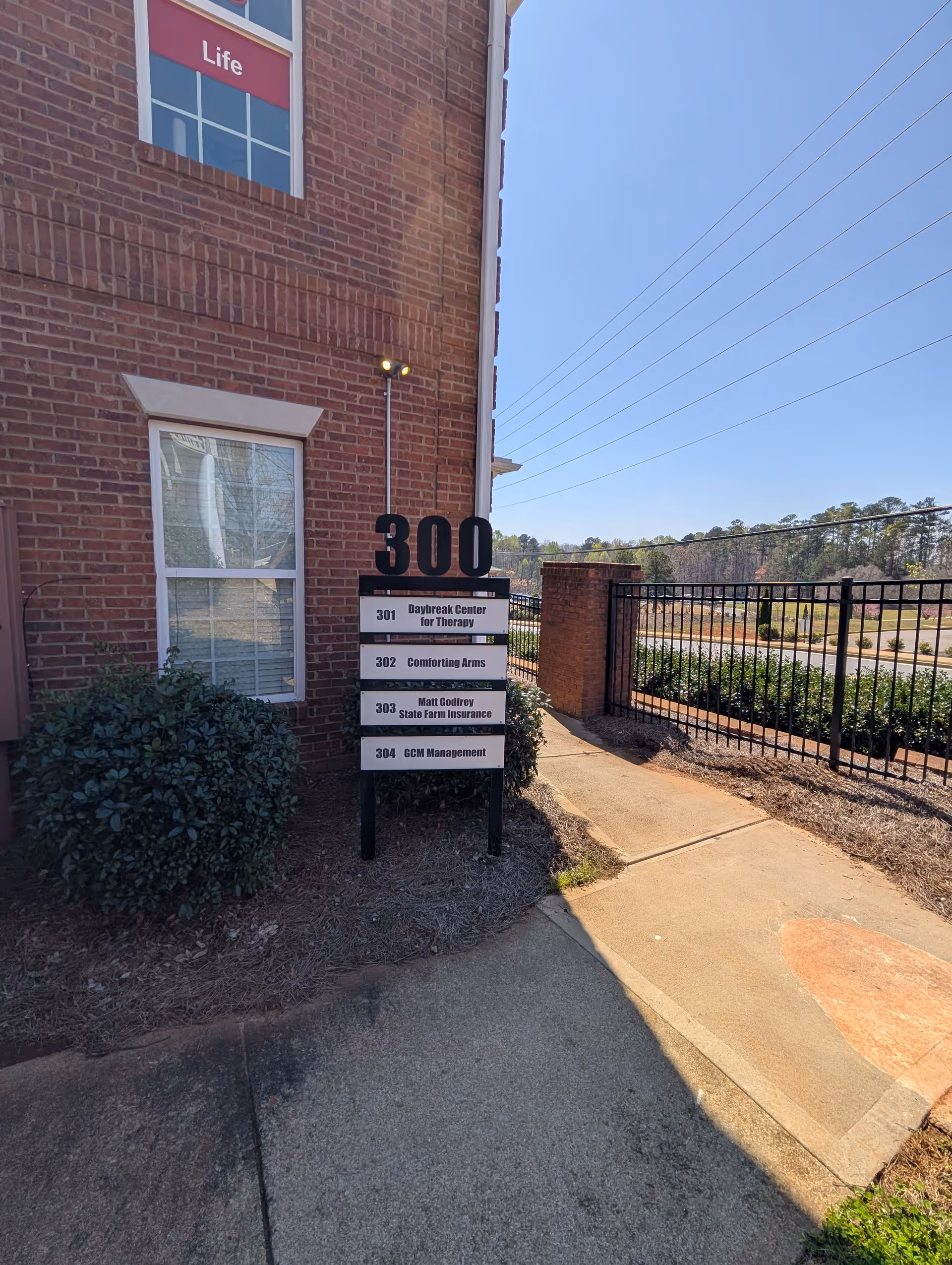 Brick building exterior with directory sign listing Comforting Arms and neighboring offices.