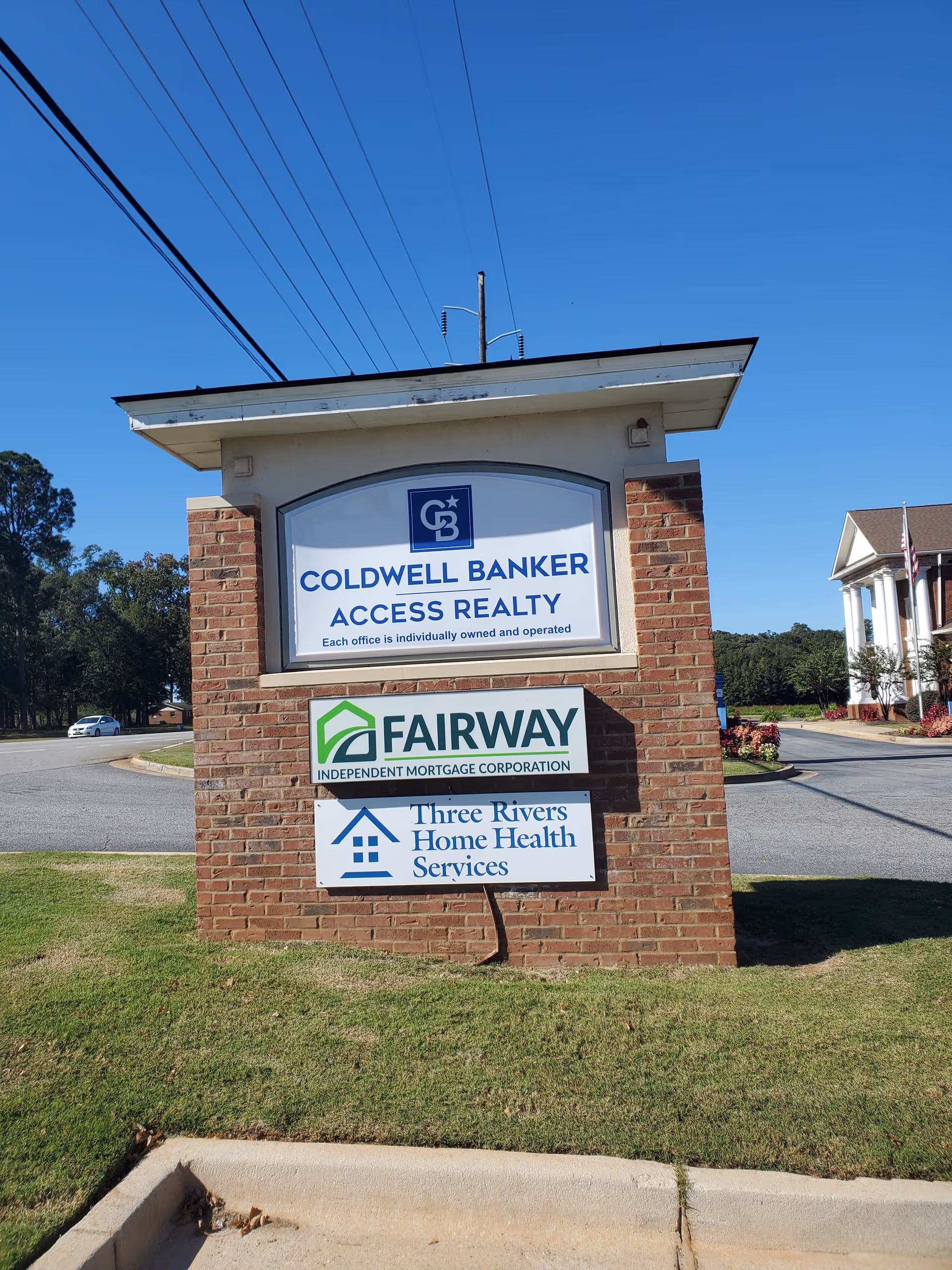 Brick sign structure displaying Coldwell Banker, Fairway Mortgage, and Three Rivers Home Health Services signs.