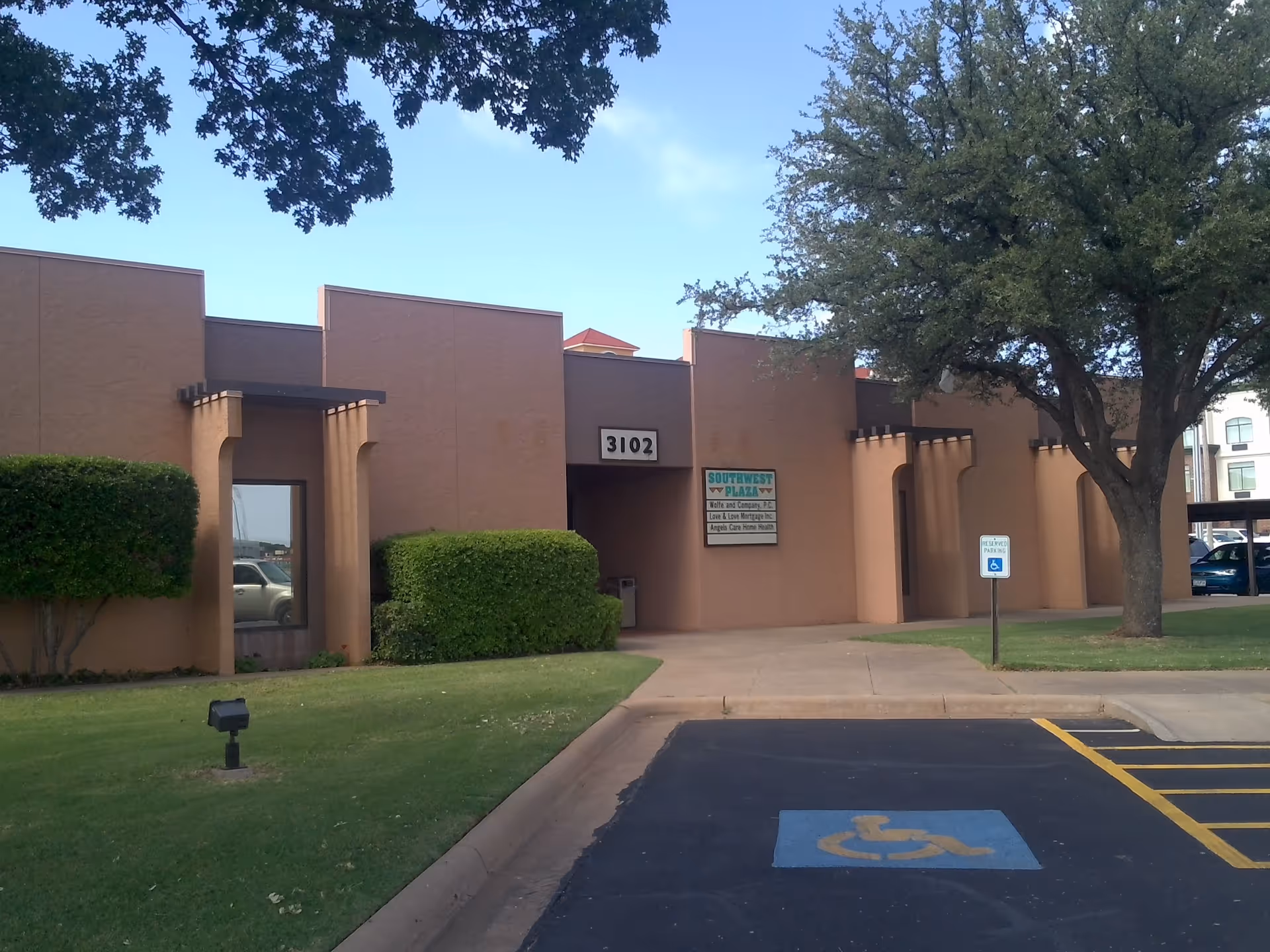 Tan, modern, single-story building with entrance and handicap parking lot in front.