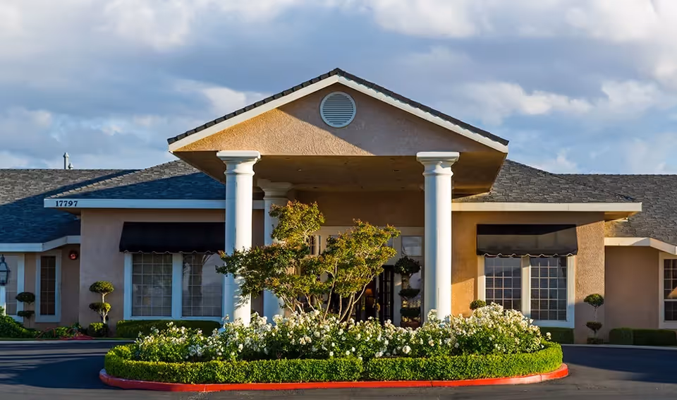 Front view of Sterling Commons Memory Care Community building with columns and landscaped entry.