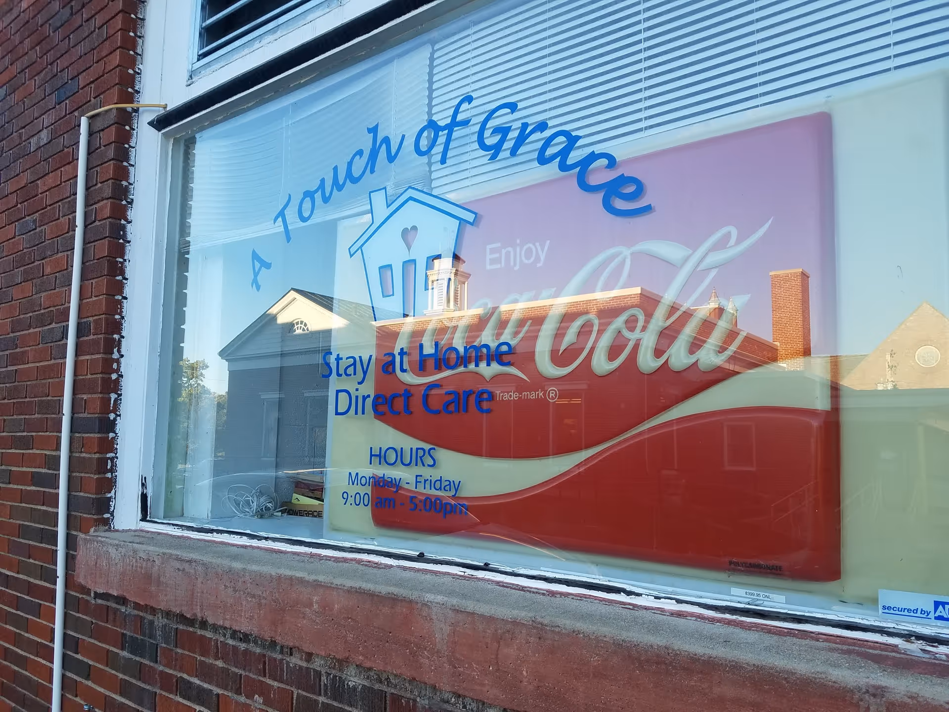 Storefront window displays A Touch of Grace sign and Coca-Cola ad reflections.
