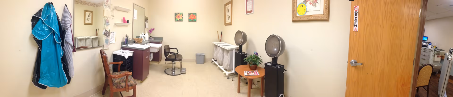 Interior senior facility room with hair salon chairs, drying hood machines, and styling stations.