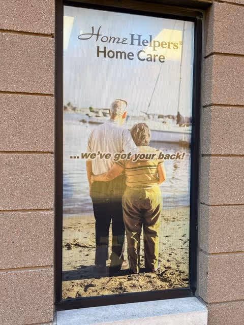 Poster in brick storefront window shows couple by the beach with slogan.