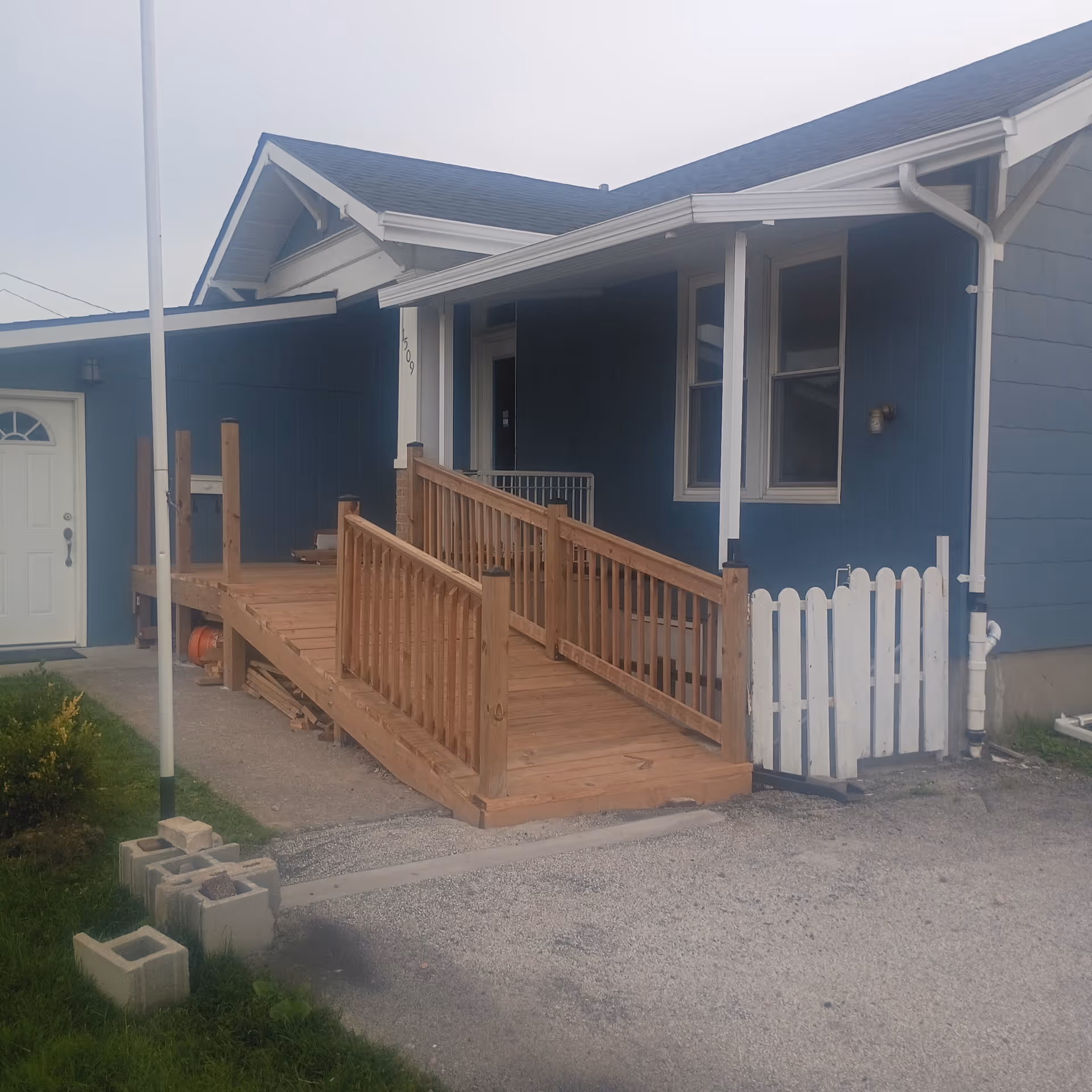 Blue single-story facility with wooden ramp, white fence, and front entrance.