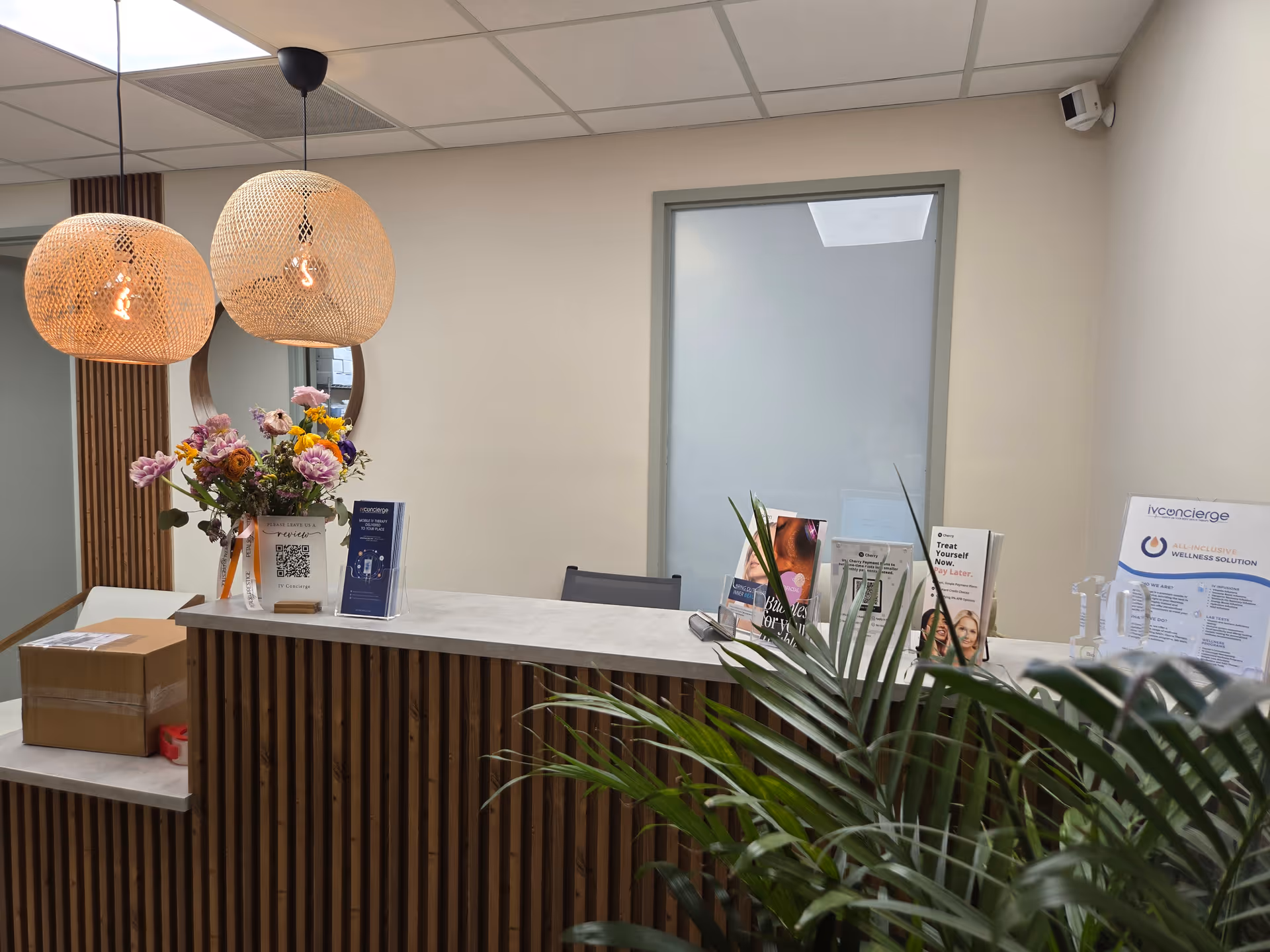 Reception desk in a modern, well-lit lobby with flowers and brochures.
