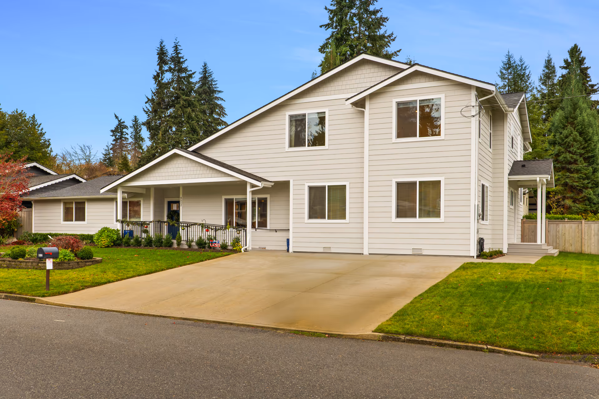 A two-story gray senior care facility with a front driveway, porch, and well-kept lawn.