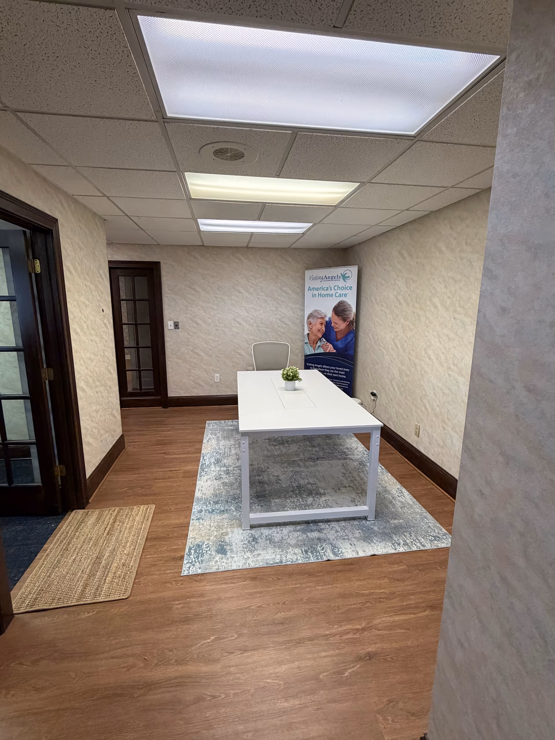 A small interior office space with a white table, chair, and promotional banner.