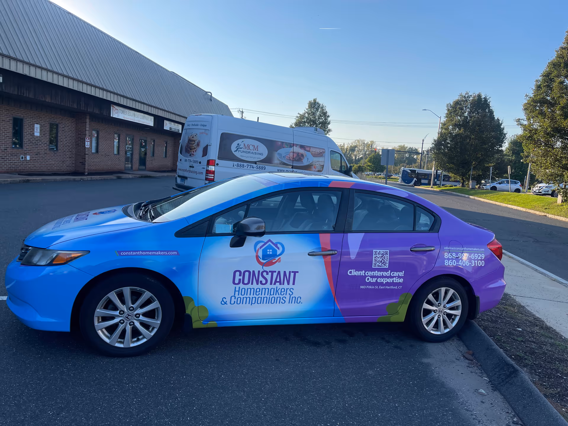 Colorful branded vehicle for Constant Homemakers & Companions parked outside a brick building.