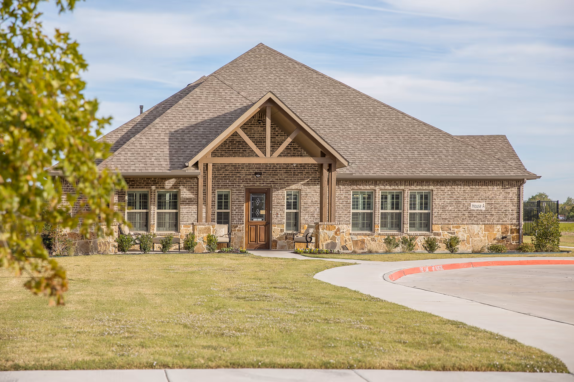 Brick senior living facility exterior with stone accents, peaked roof, and landscaped entrance.