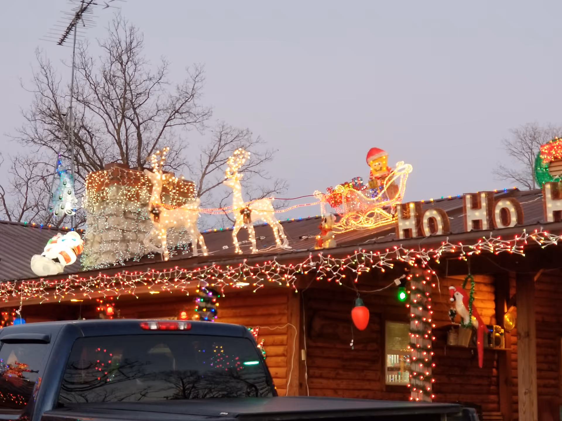 Exterior wooden care center facade adorned with Christmas lights, reindeer, Santa, and Ho Ho Ho.