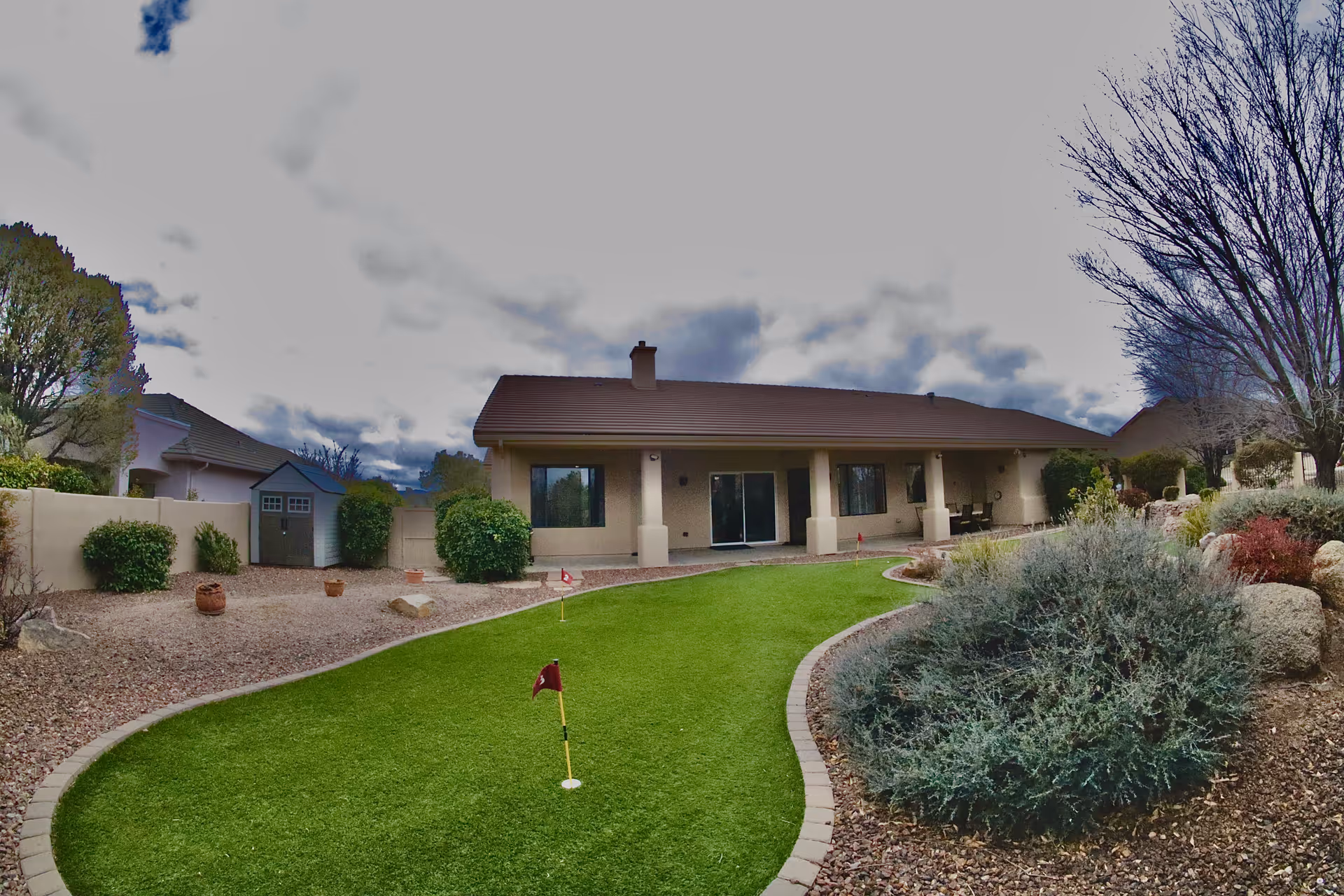 Single-story building with landscaped outdoor space, putting green, and desert plants.