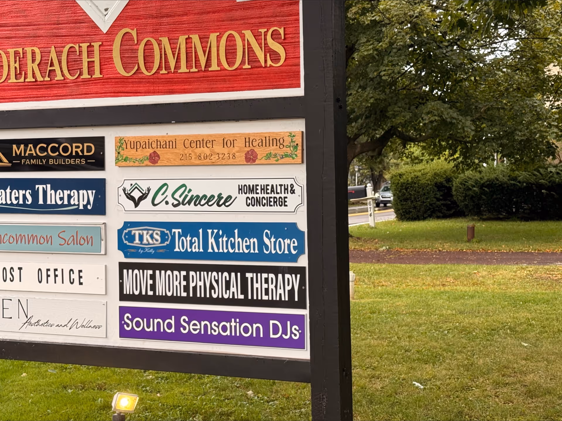 Large outdoor signboard on a lawn advertising multiple businesses, including C. Sincere Home Health & Concierge.