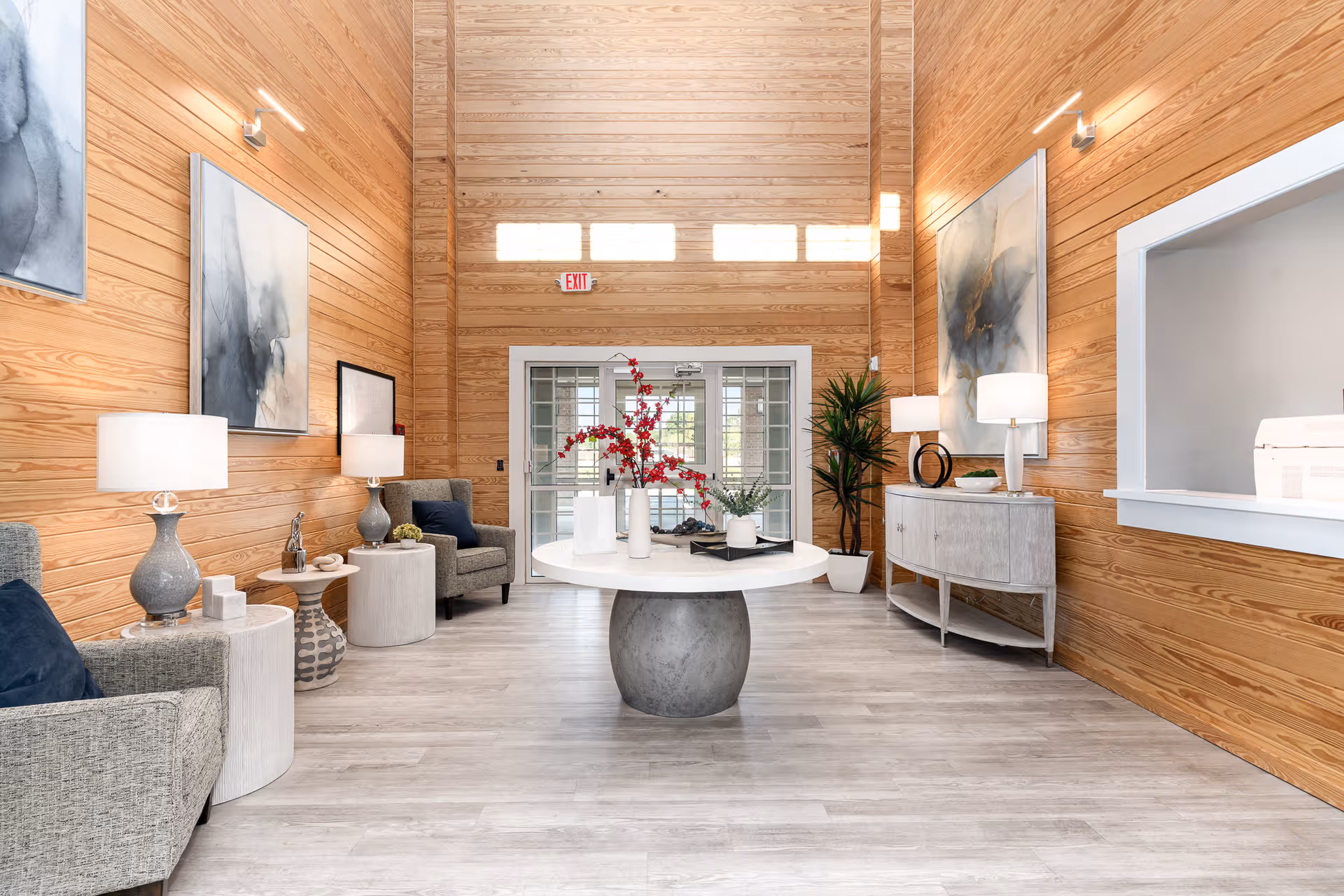 Wood-paneled lobby with round central table, seating, and modern decor.