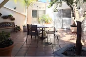 Outdoor patio courtyard with table, chairs, and potted plants under trees.