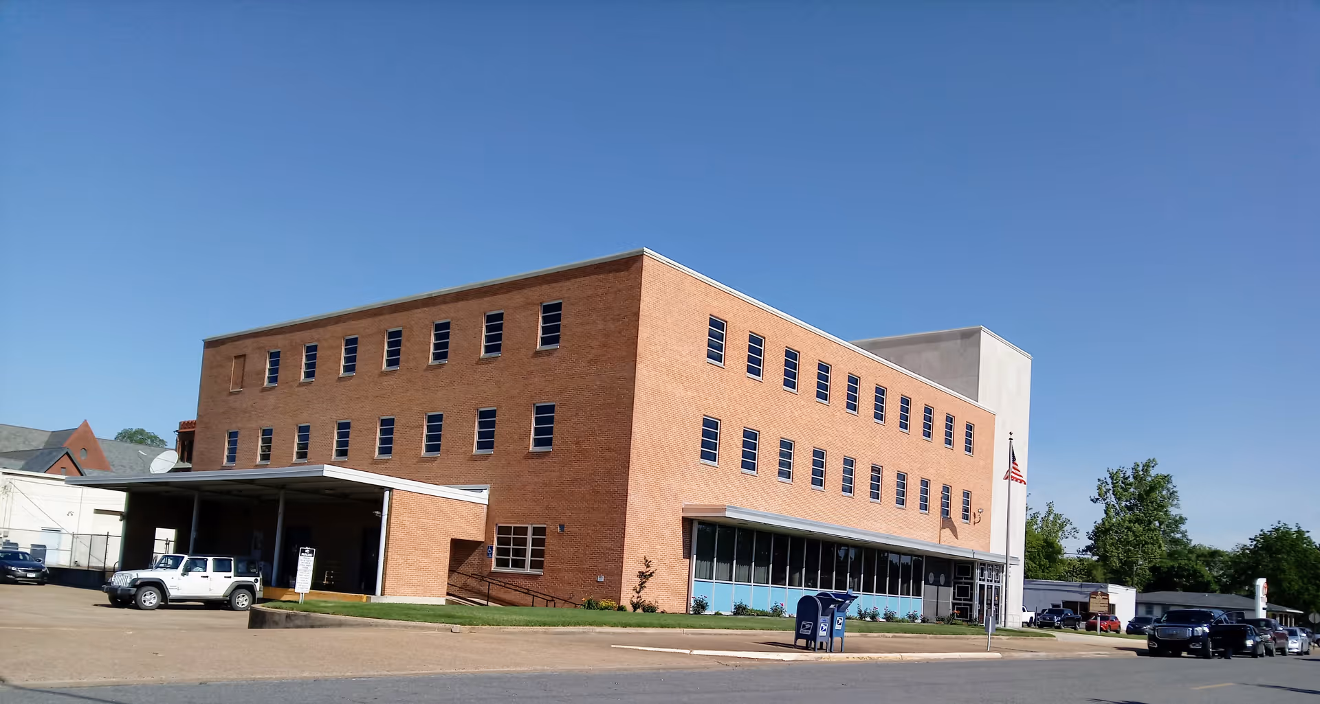Brick East Ark Area Agency On Aging building with parking lot and clear sky.