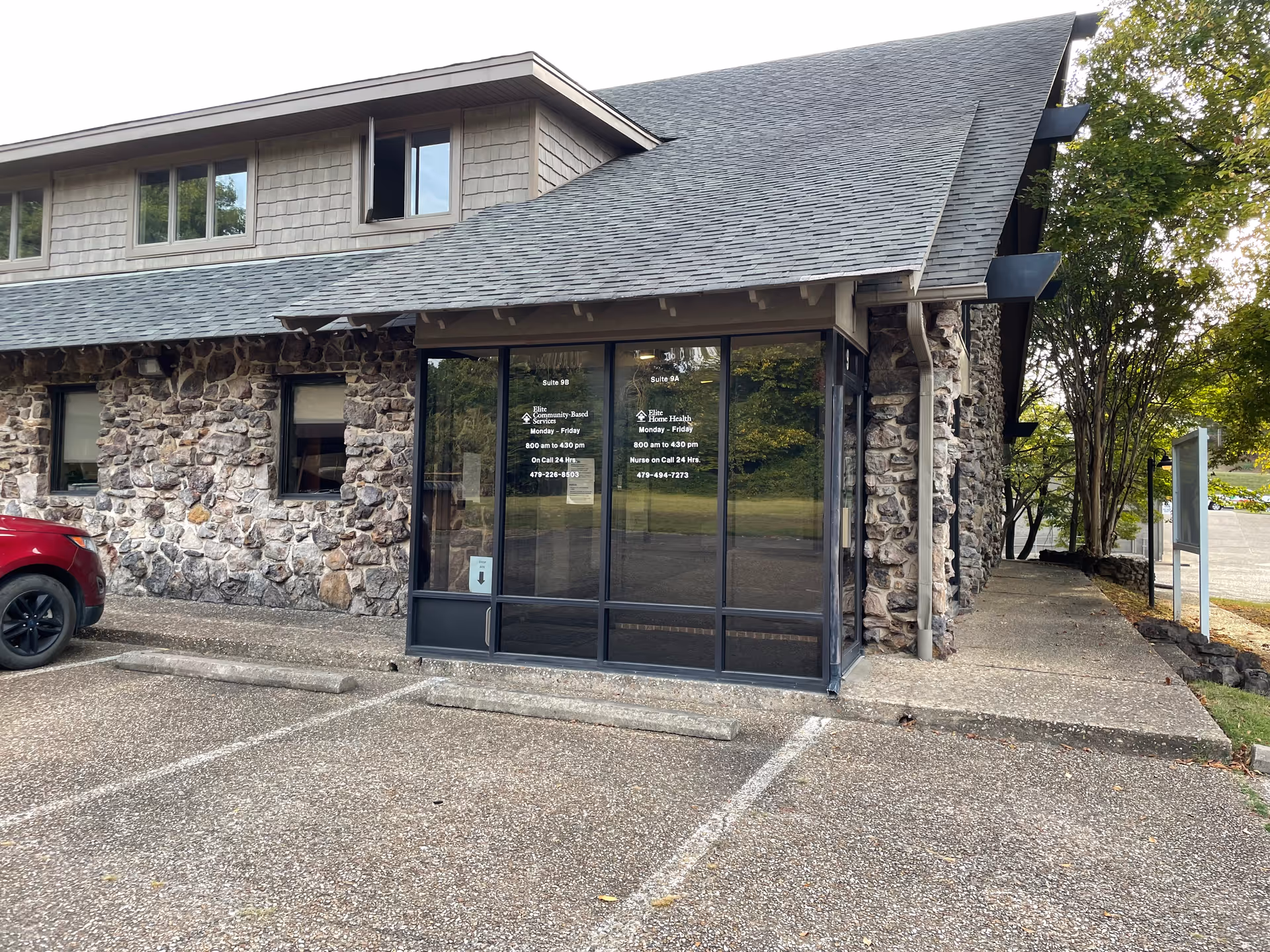 Stone-faced building entrance with glass doors and a parking lot.