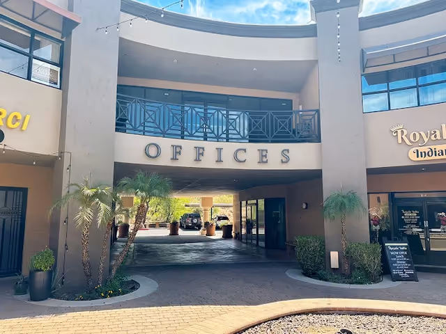 Exterior of a building front with an archway labeled OFFICES and palm trees.