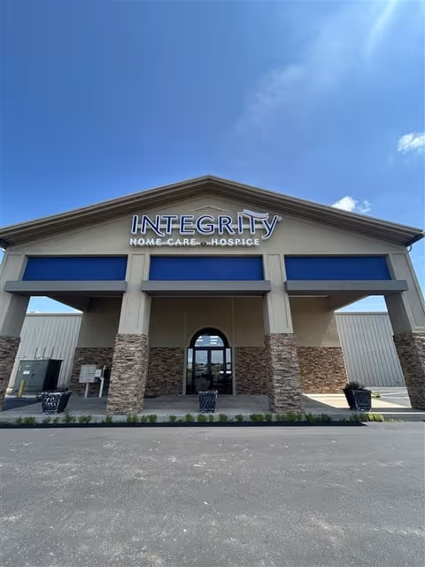 Front view of a beige building with stone columns and blue awnings.