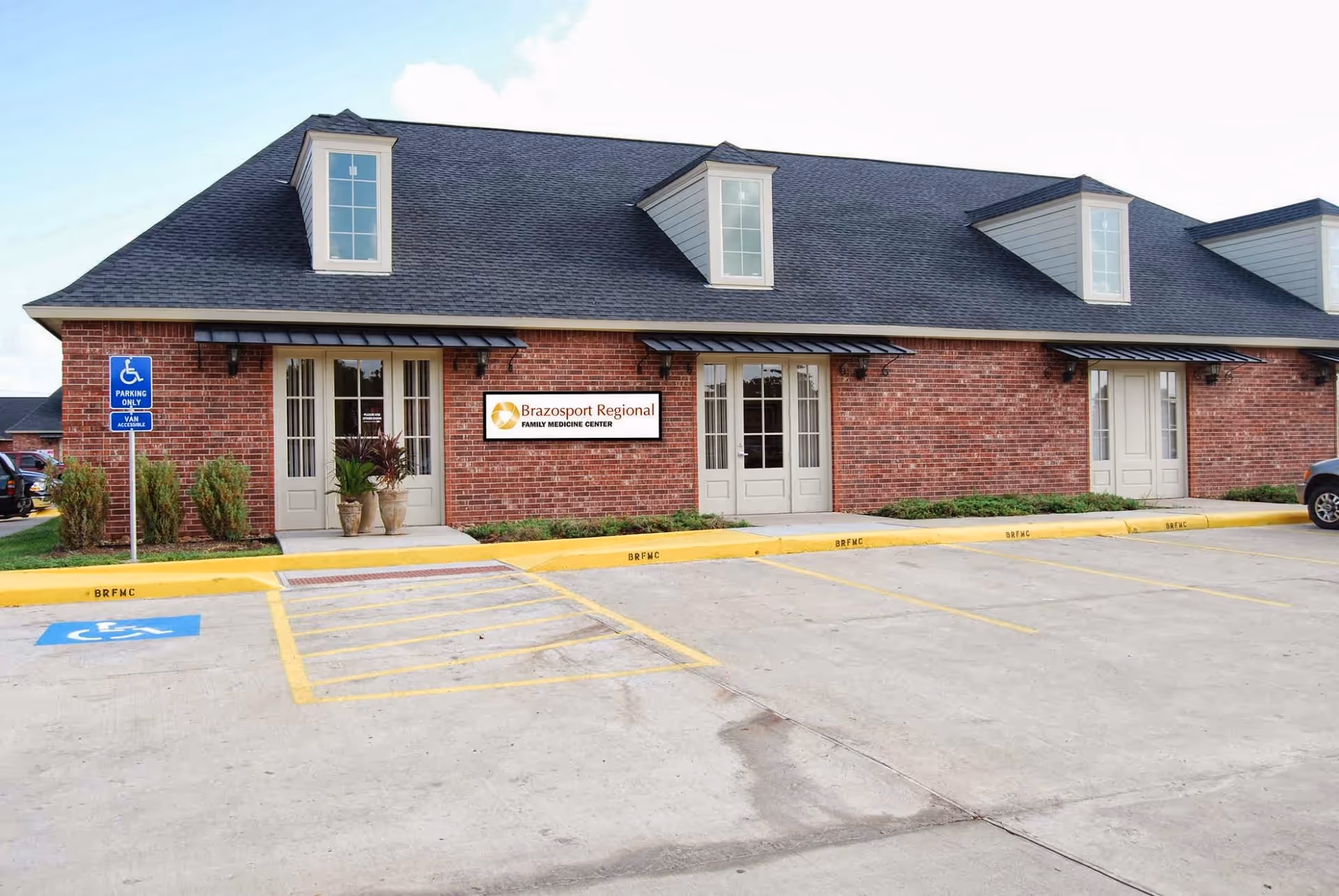 A brick medical office building with a parking lot and handicapped space in front.