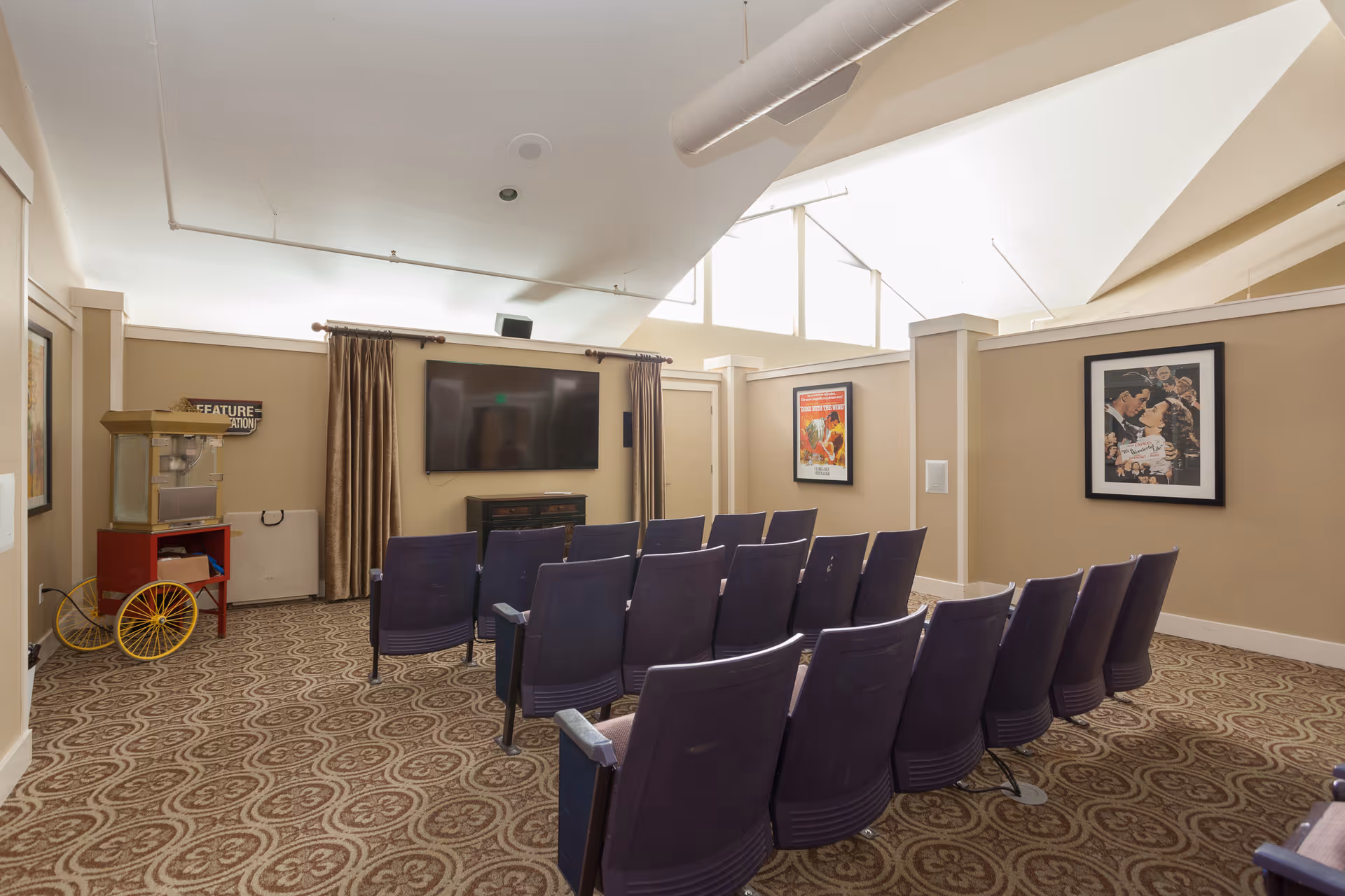 Interior media room with purple theater chairs facing a wall-mounted screen.