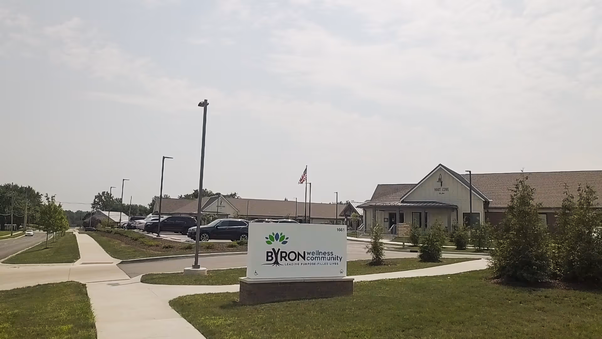 Exterior view of Byron Health Center with sign, parking lot, and surrounding landscaping.