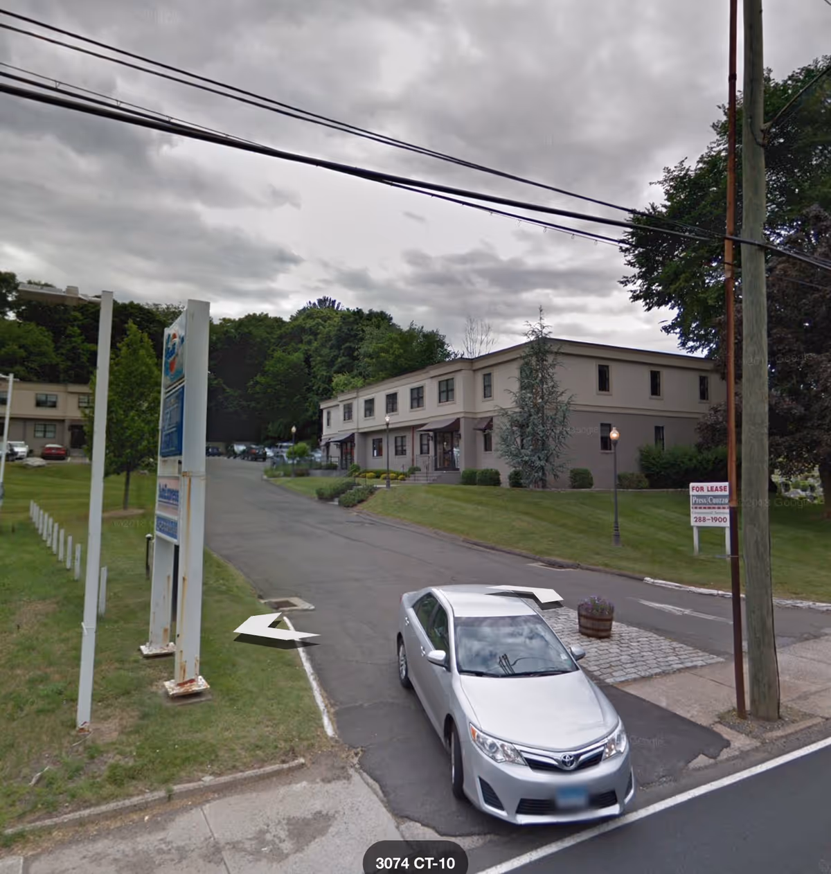 Two-story beige senior care facility on a curved road with a parked silver car.