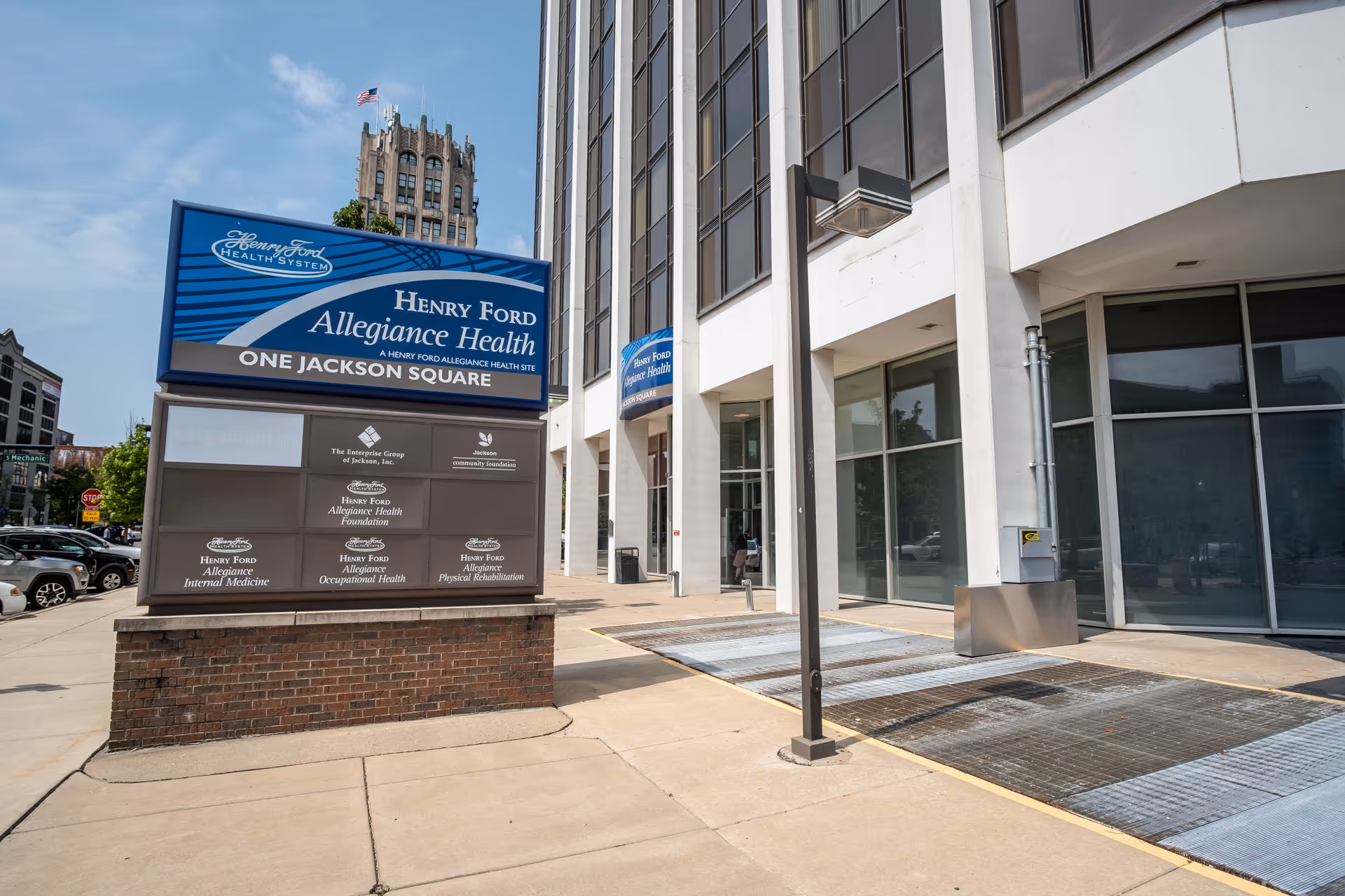 Modern building exterior with a large blue Henry Ford Allegiance Health sign on a brick pedestal.