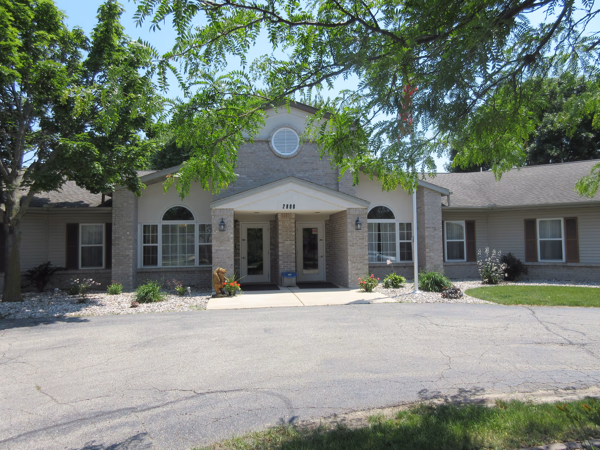 Exterior view of Westminster Palms senior living facility entrance with trees and landscaping.