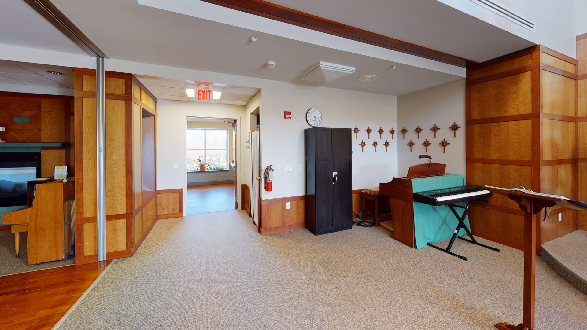 Interior common area featuring a piano, keyboard, crosses on wall, and corridor.