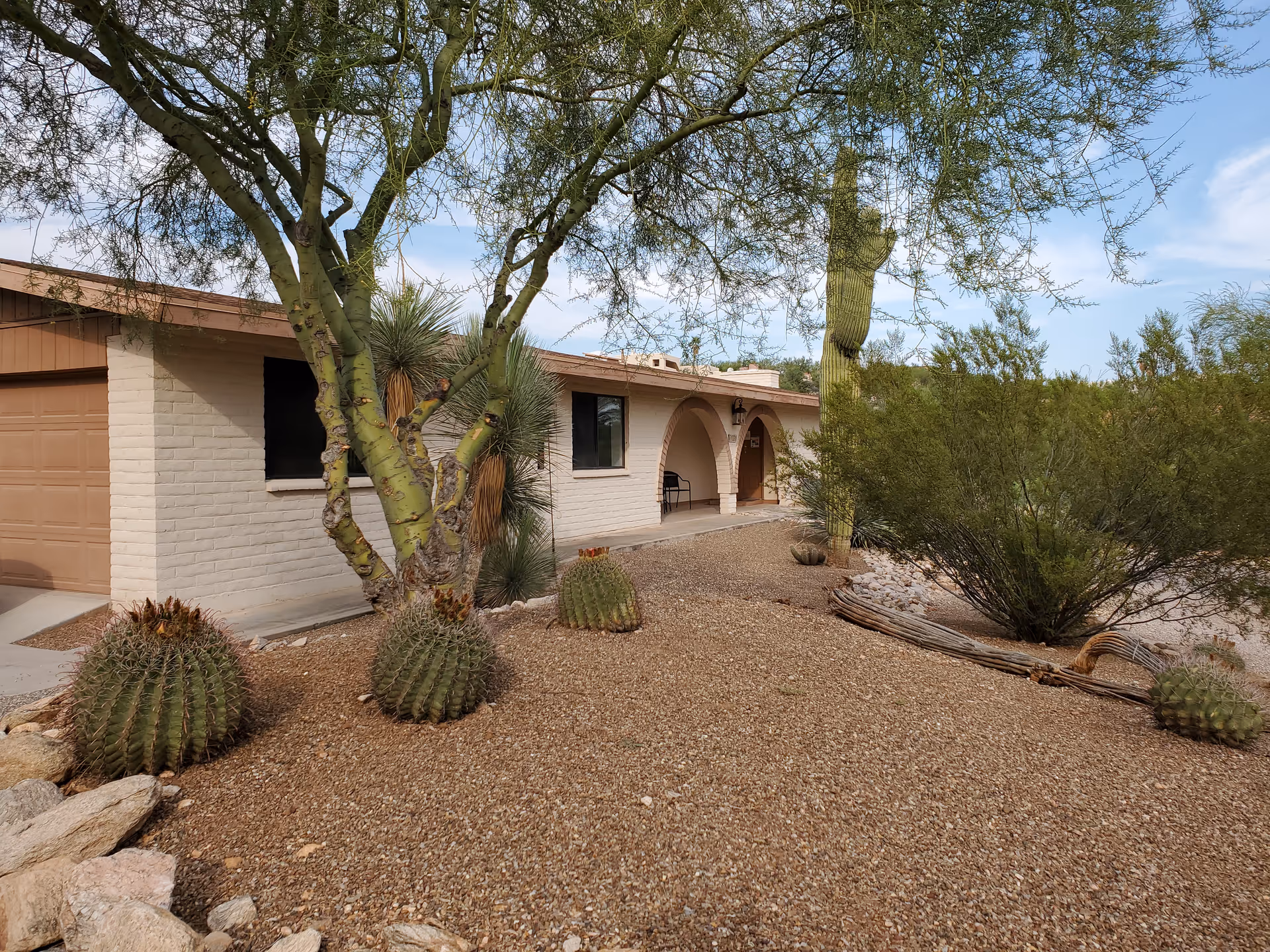 Single-story beige building with arched entrance and desert landscaping in front.