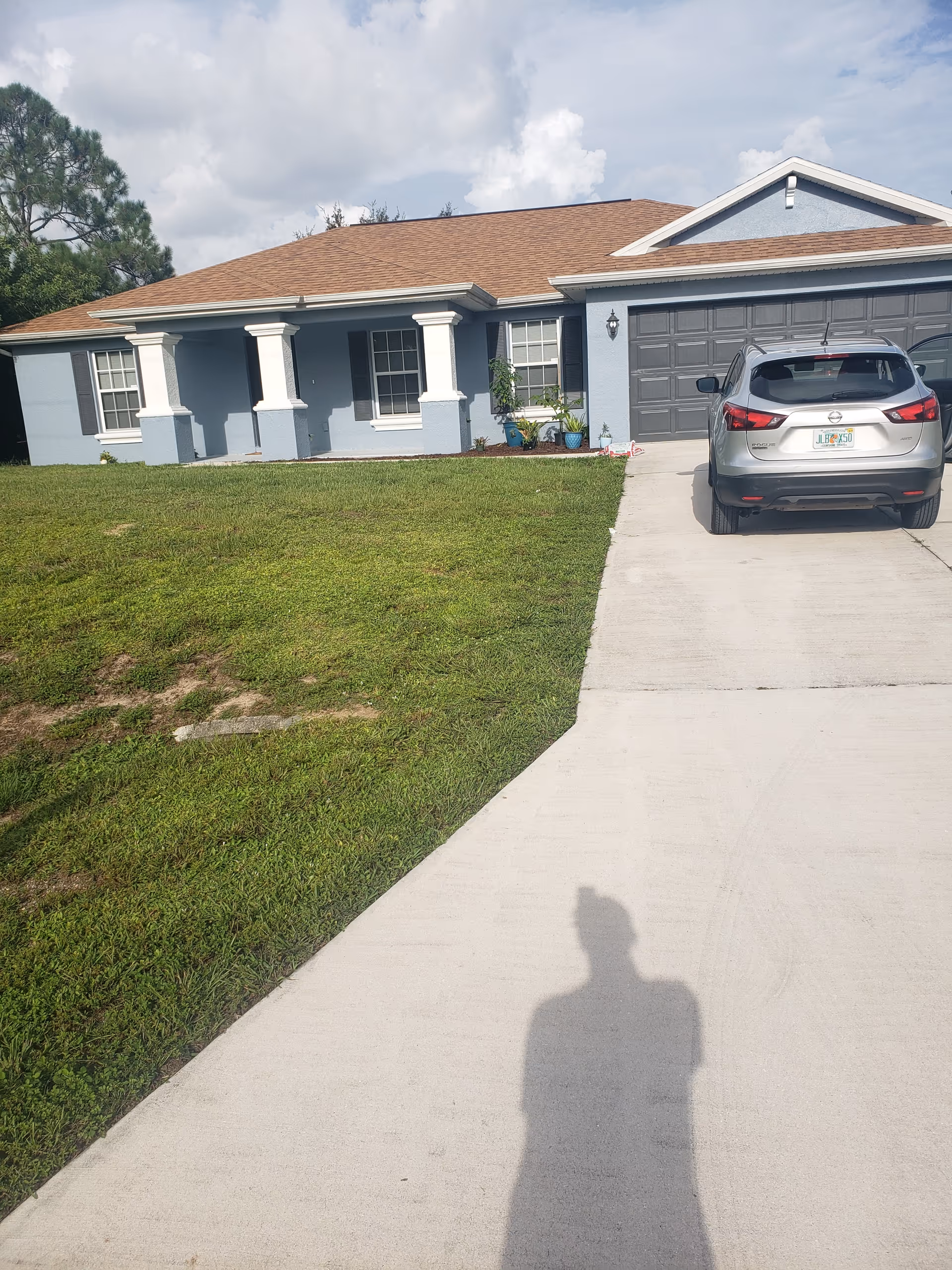Blue single-story house with driveway, parked SUV, and well-kept front lawn.