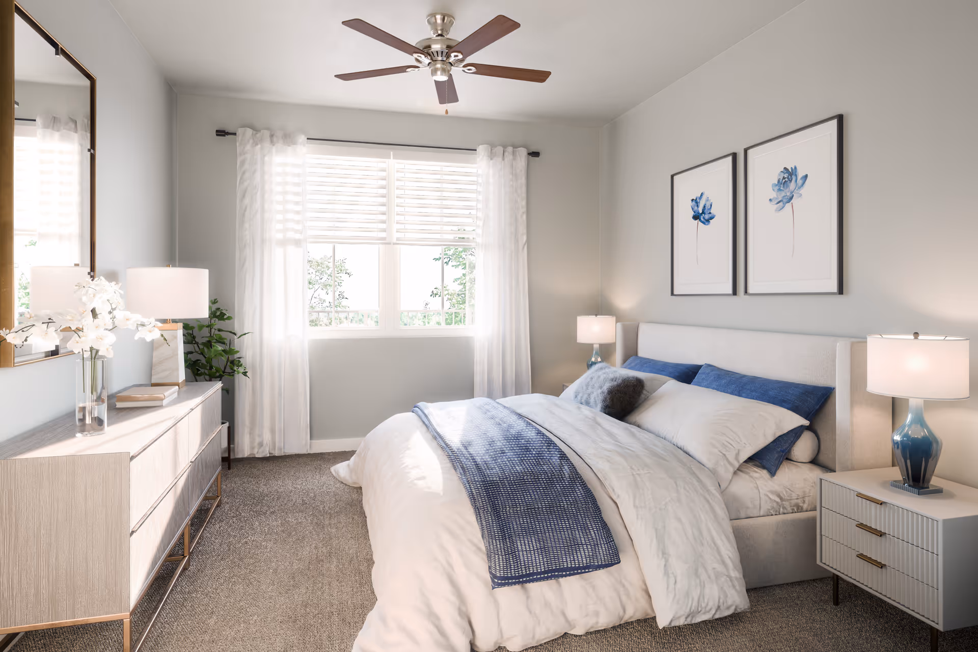 Sunlit, contemporary bedroom featuring a bed with blue accents, matching nightstands and lamps, a dresser with mirror, ceiling fan, and a window with sheer curtains.