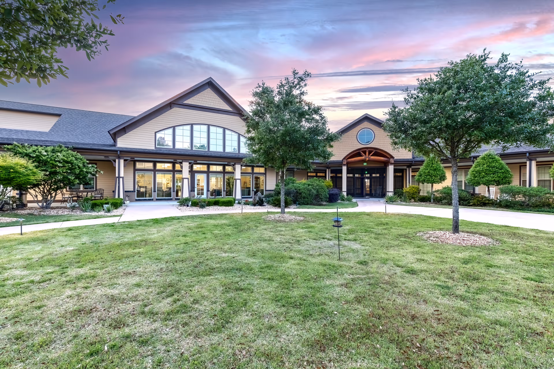 The front view of a senior living facility with a manicured lawn and entrance.
