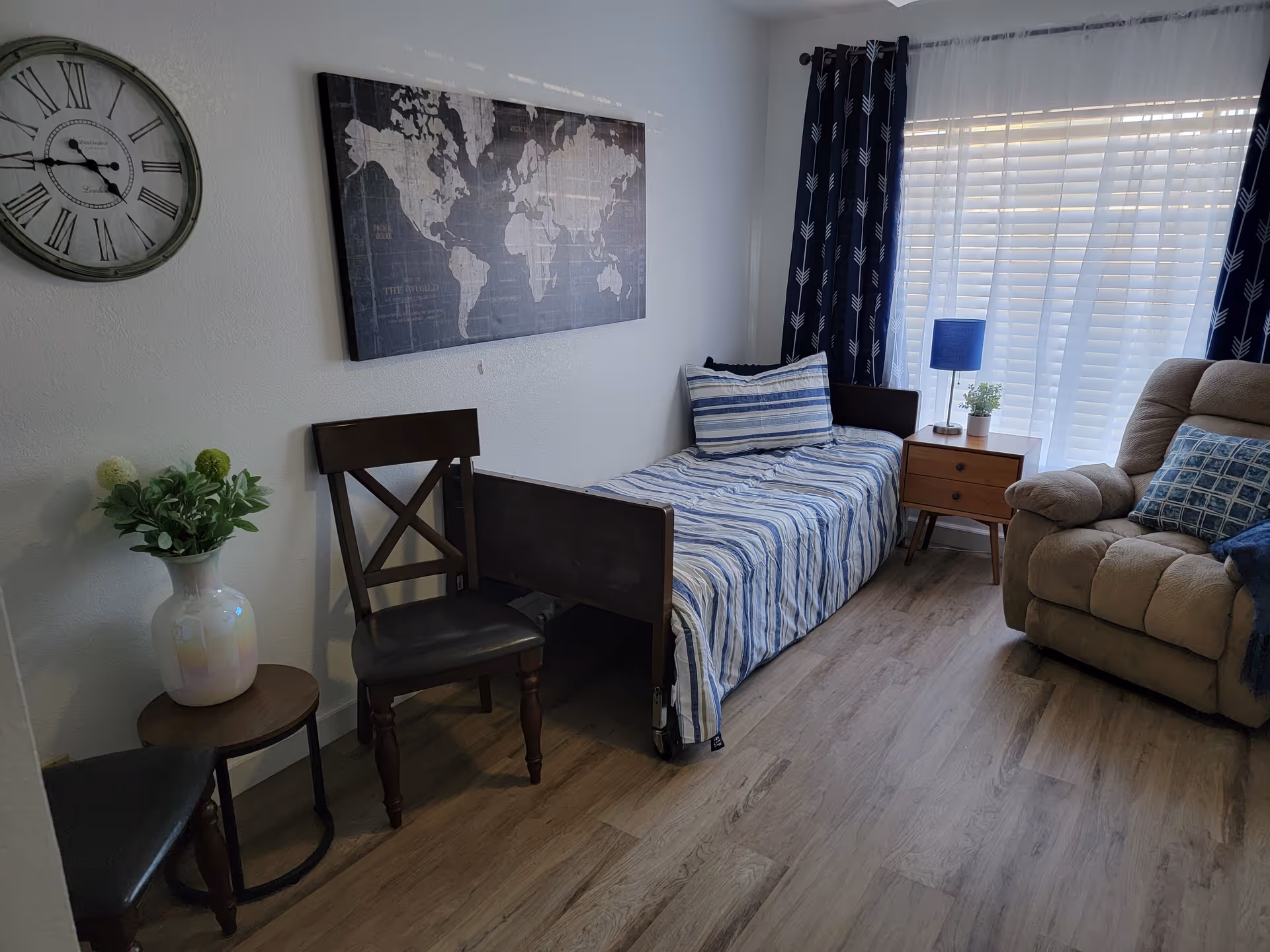 Interior living area in a senior home with a daybed, sofa, chair, and window curtains.