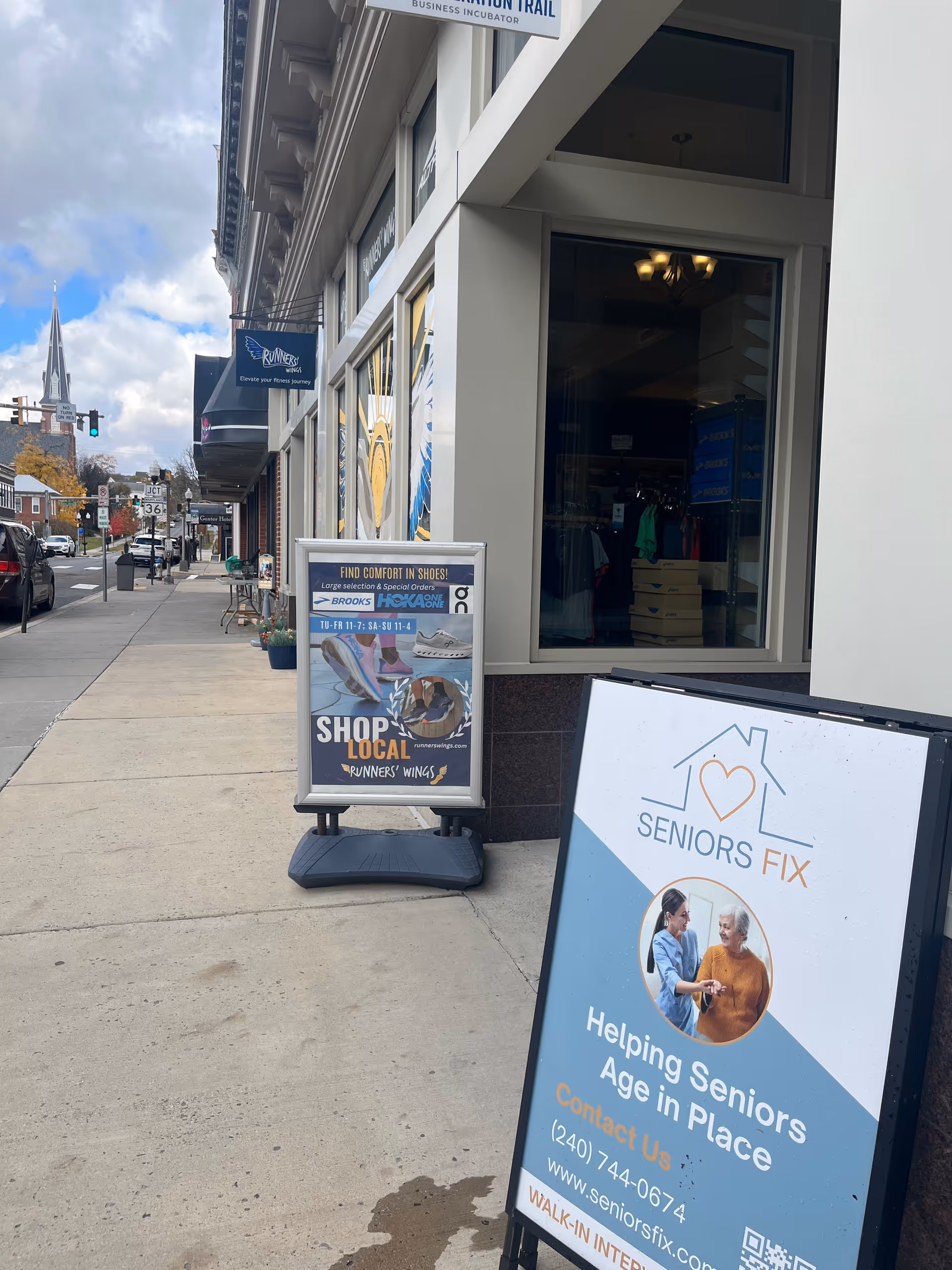 Storefront along city sidewalk featuring Seniors Fix signage and advertising boards.