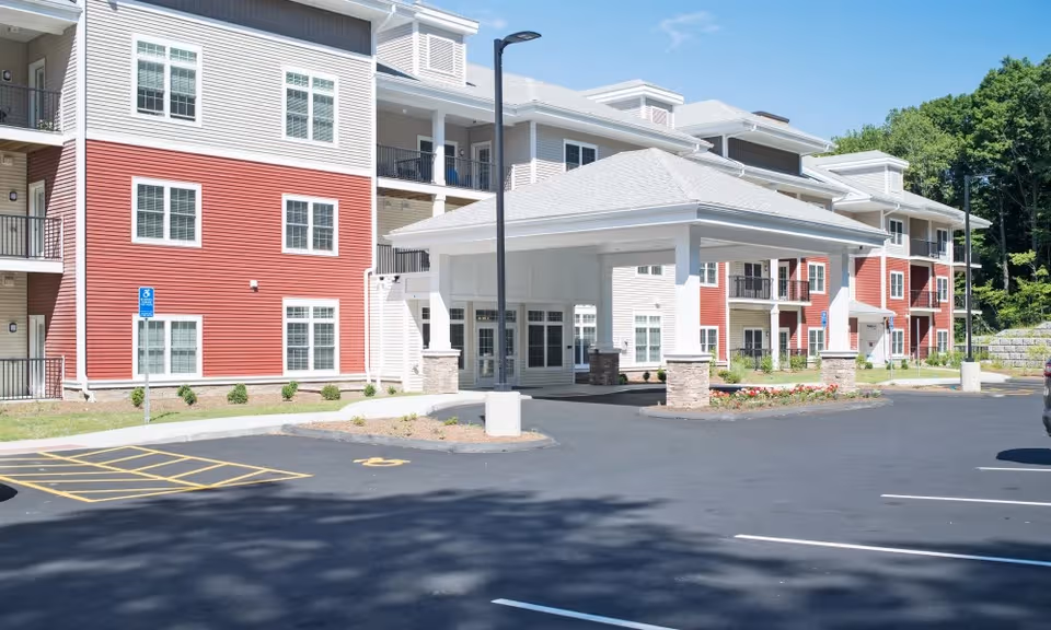 Exterior view of Keystone Place at Wooster Heights showing a red-and-white senior living building and parking.