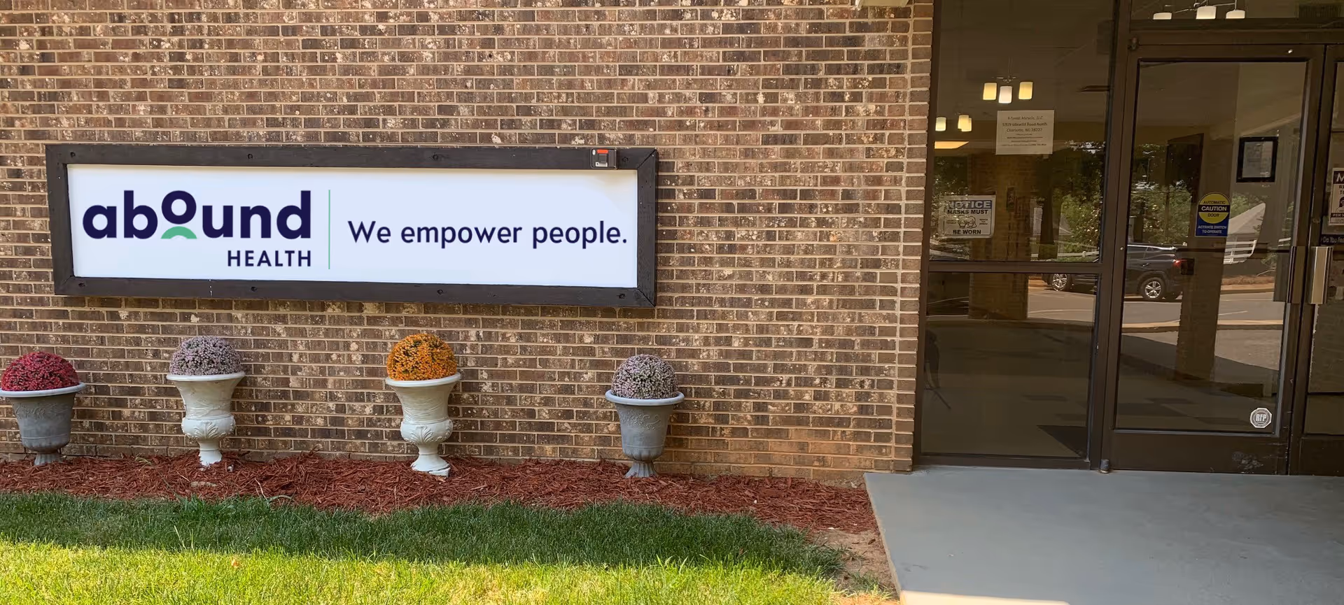 Exterior view of Abound Health entrance with sign and decorative planters.