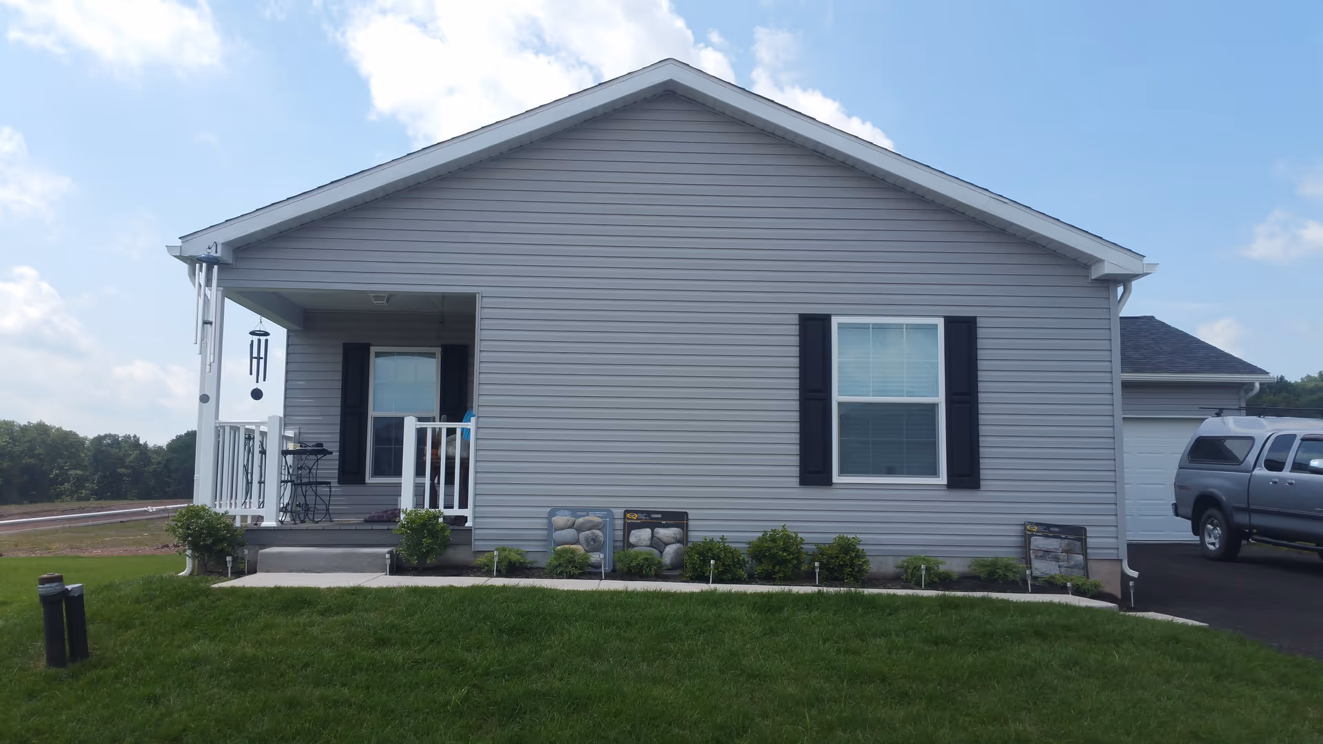 Single-story, house-style senior living facility with front porch, green lawn, and parked SUV.
